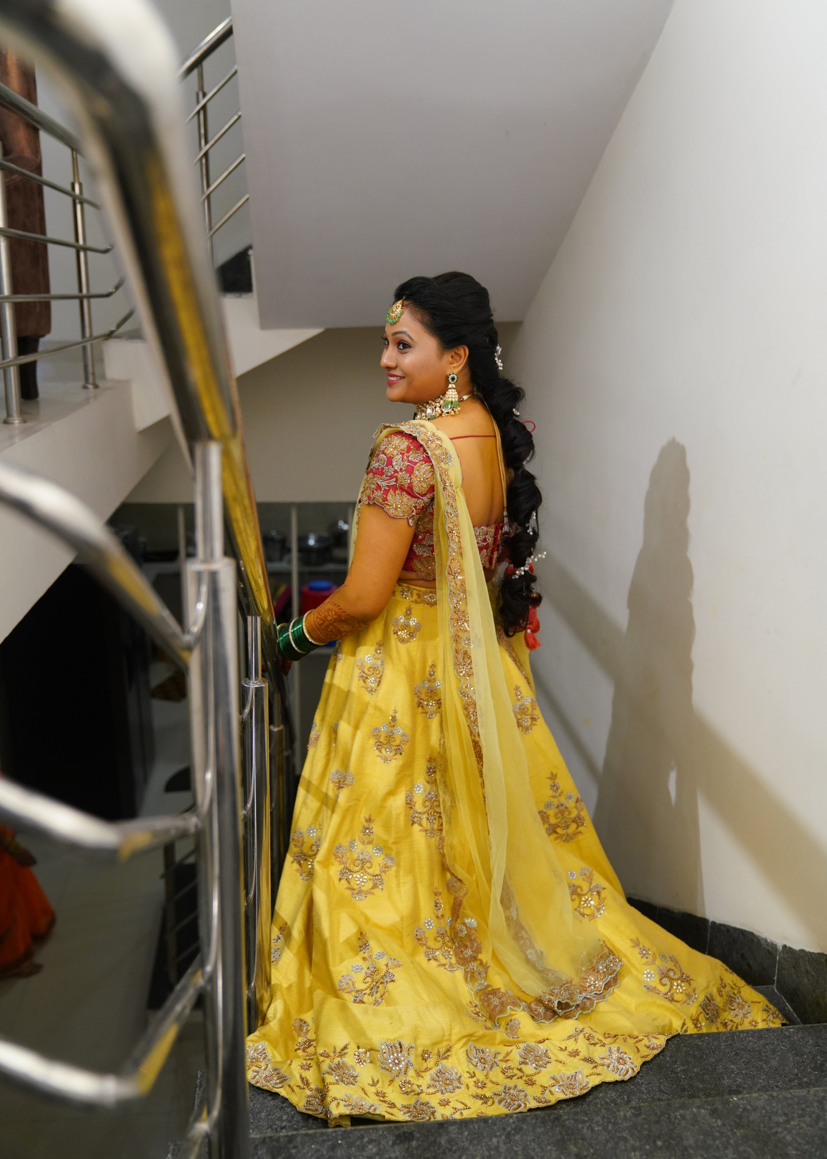 Bride from Seattle smiling in a yellow and red raw silk and yellow tulle dupatta handcrafted with zari, beads, cutdanas and sequins. Designed by Archana Karthick.