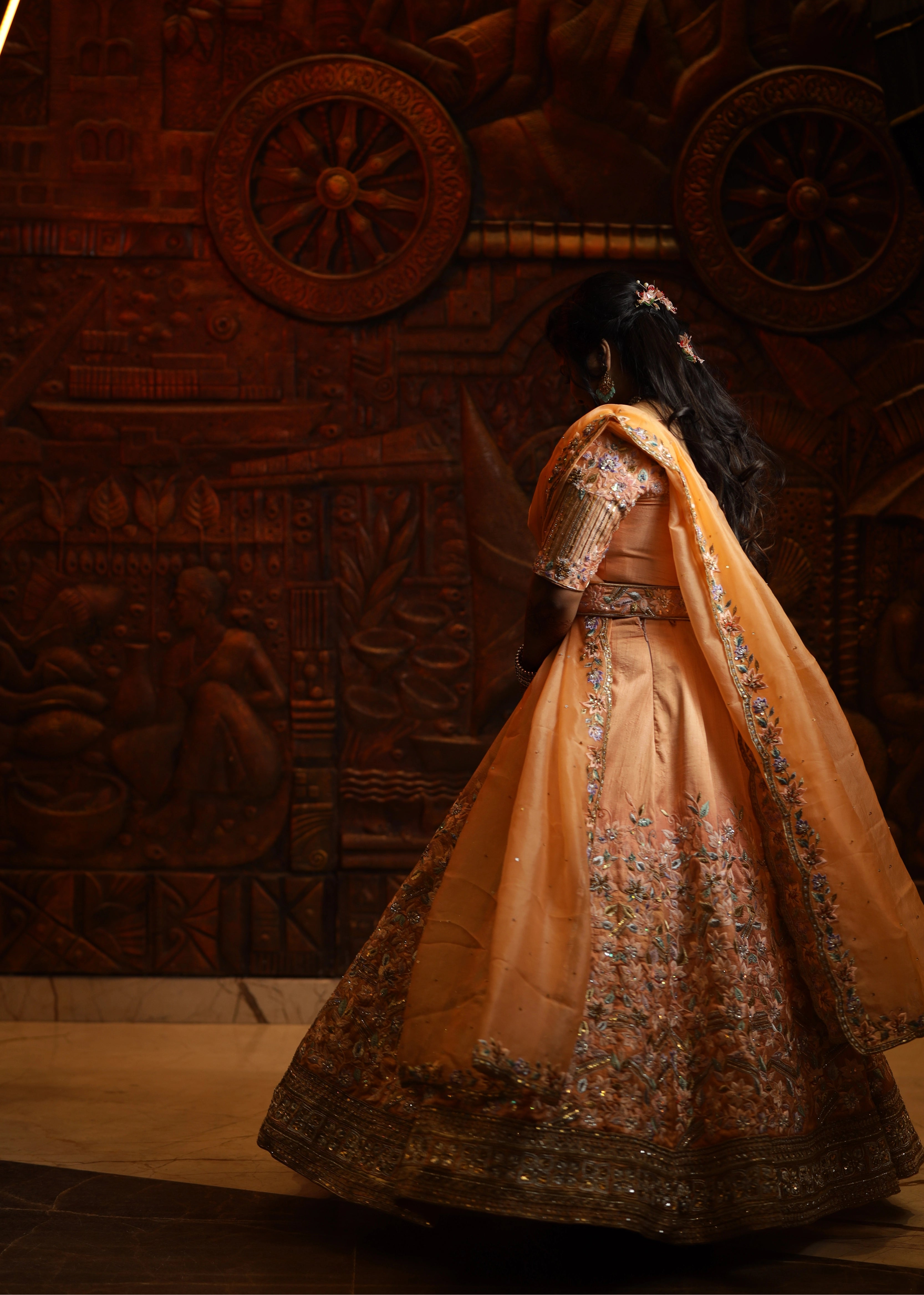 Bride from Singapore showcasing back design in a handcrafted peach lehenga designed by Archana Karthick