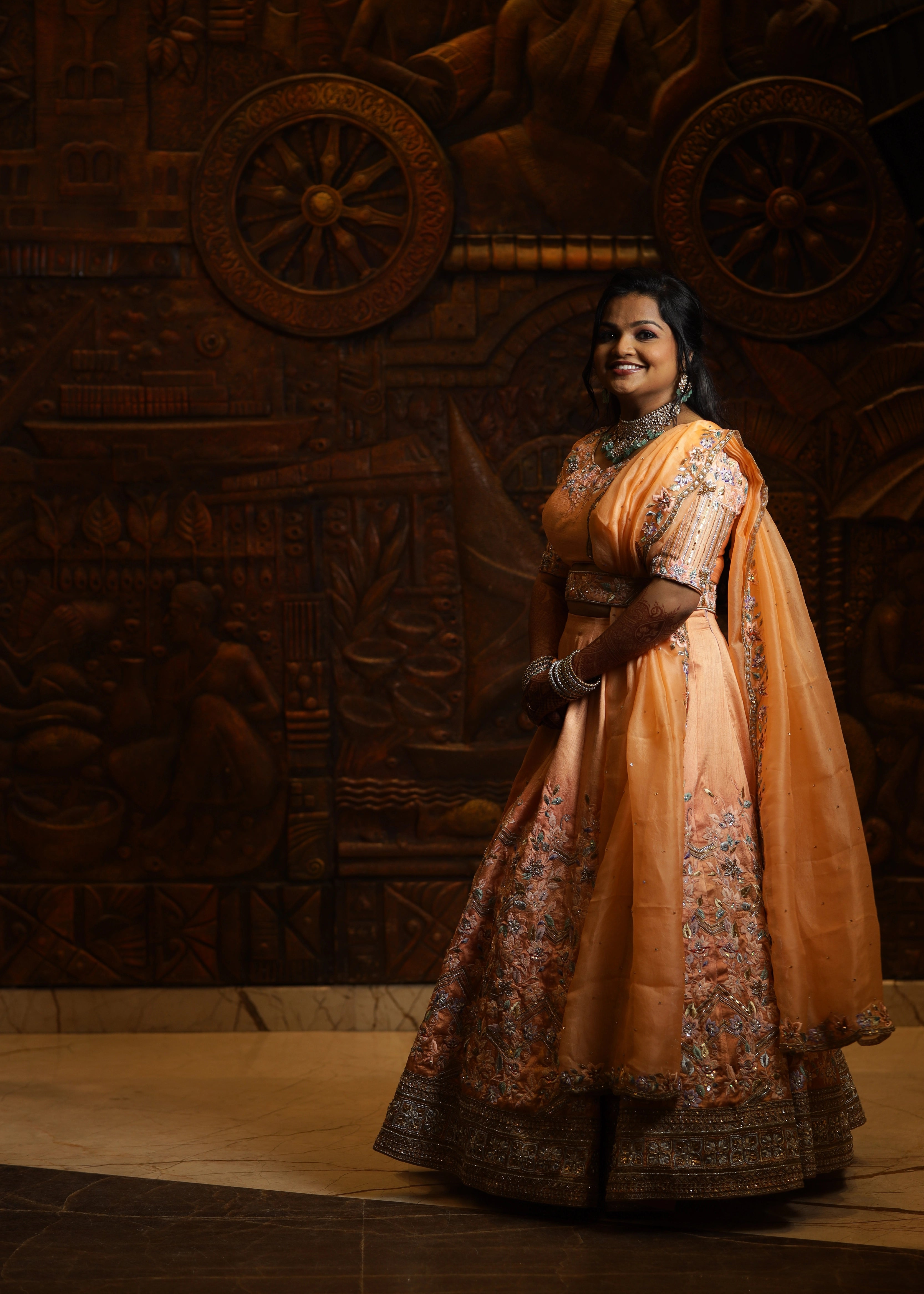 Bride from Singapore smiling in a handcrafted peach lehenga designed by Archana Karthick