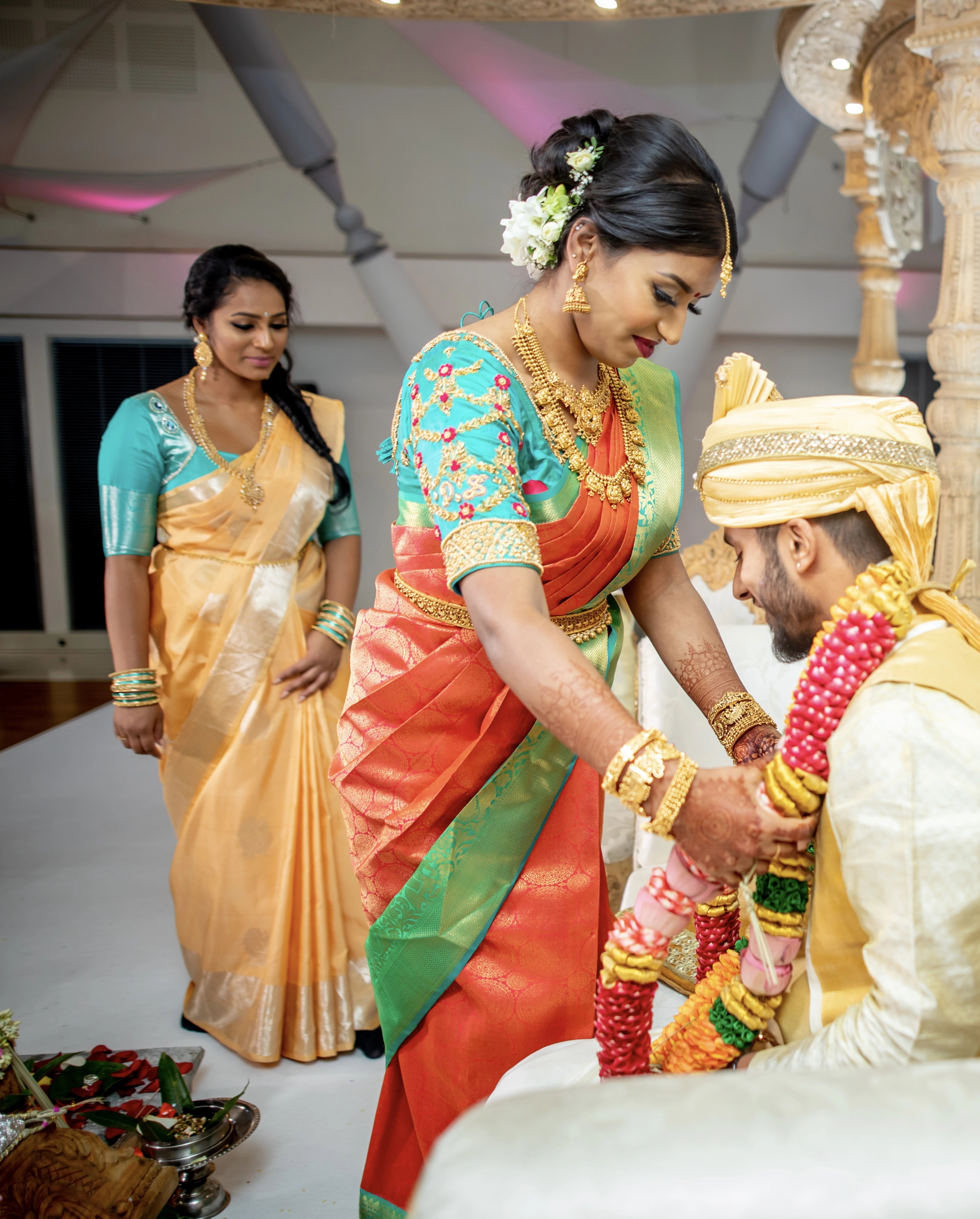 Bride from UK on stage with groom in an aquamarine silk blouse for her wedding. Handcrafted intricately with beads, zardozi and resham knot work by team Archana Karthick.