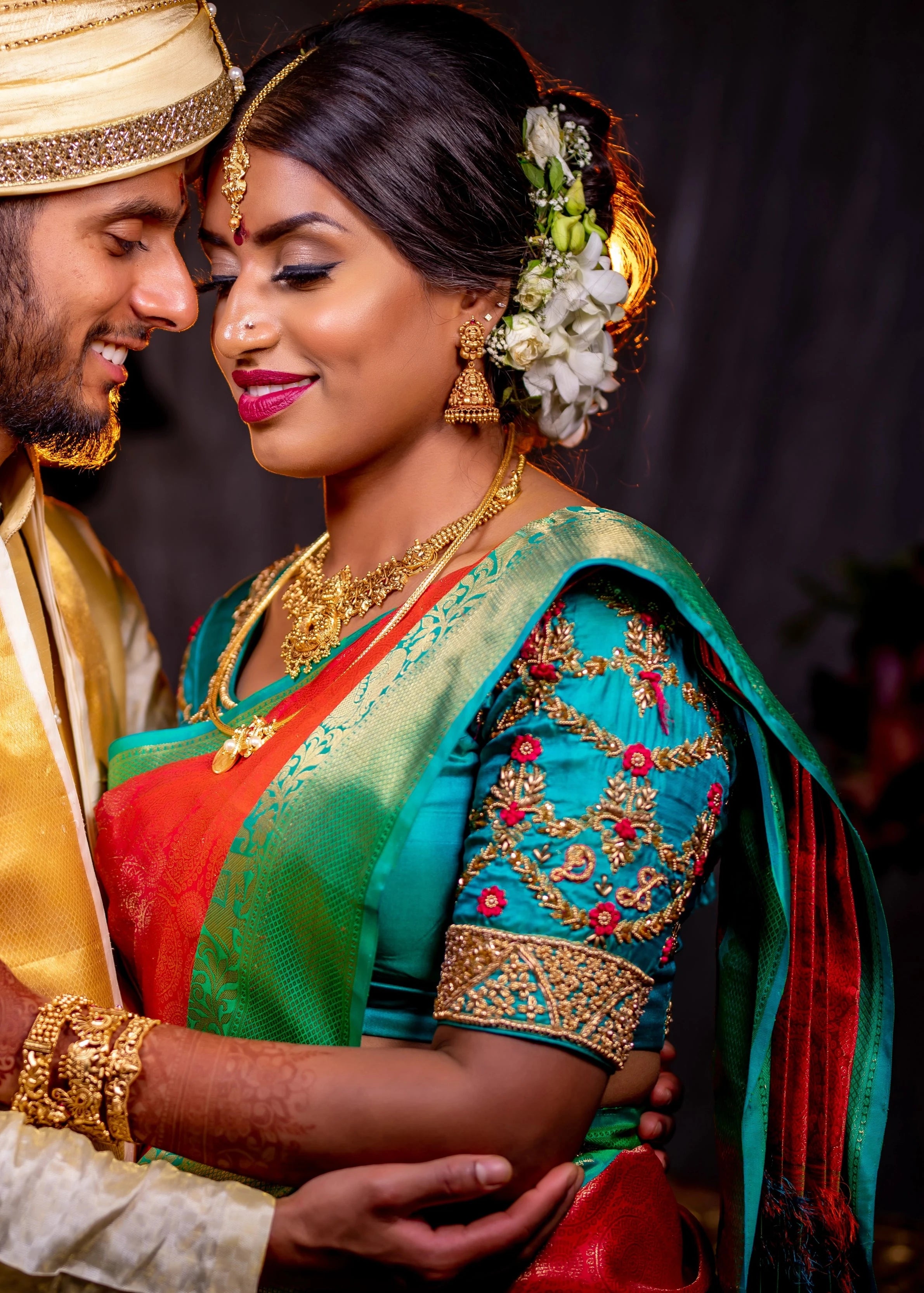 Bride from UK posing with groom in an aquamarine silk blouse for her wedding. Handcrafted intricately with beads, zardozi and resham knot work by team Archana Karthick.
