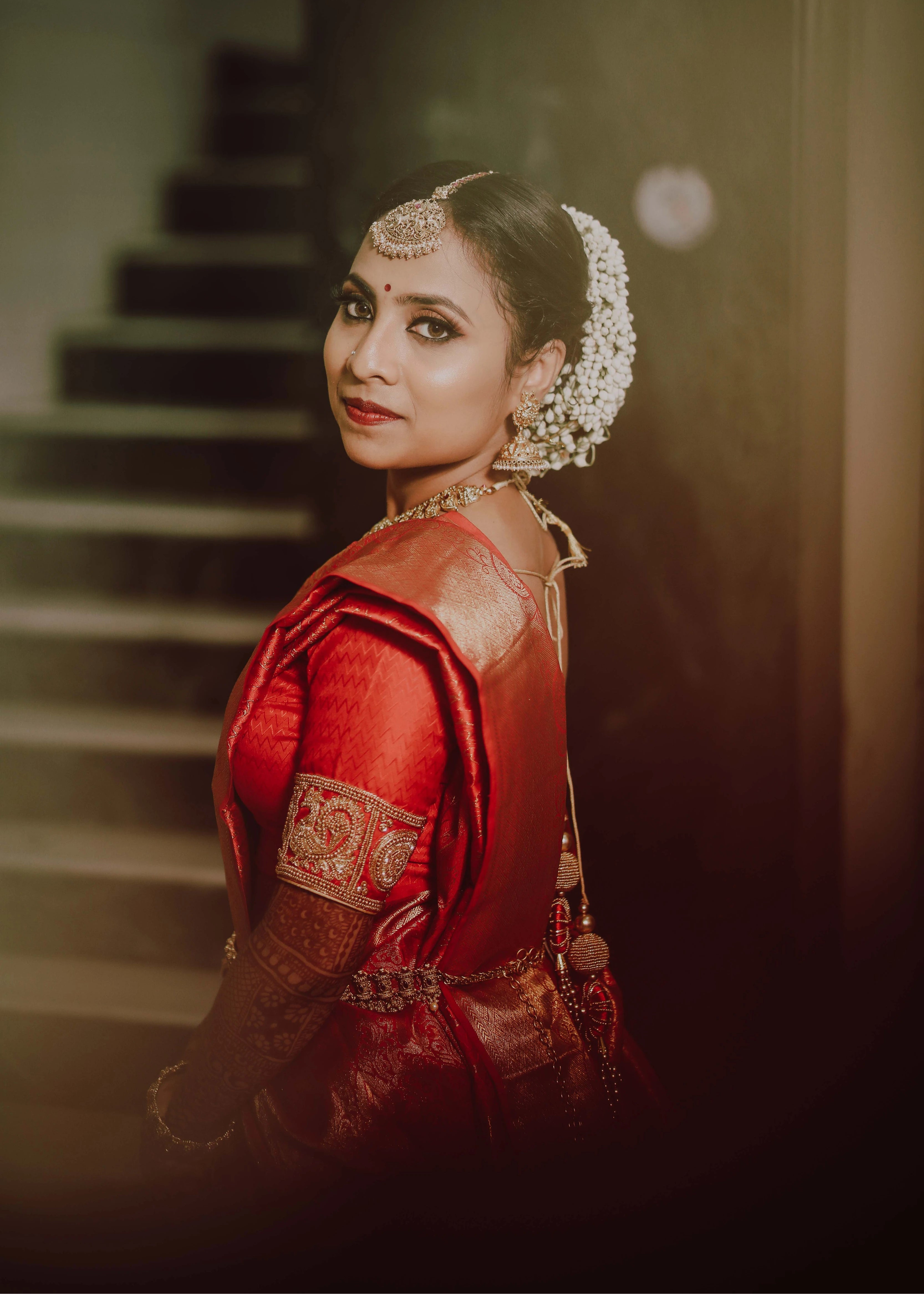 Bride from USA in a red silk blouse for her engagement ceremony. Handcrafted intricately with beads, zardozi and sequins by team Archana Karthick.