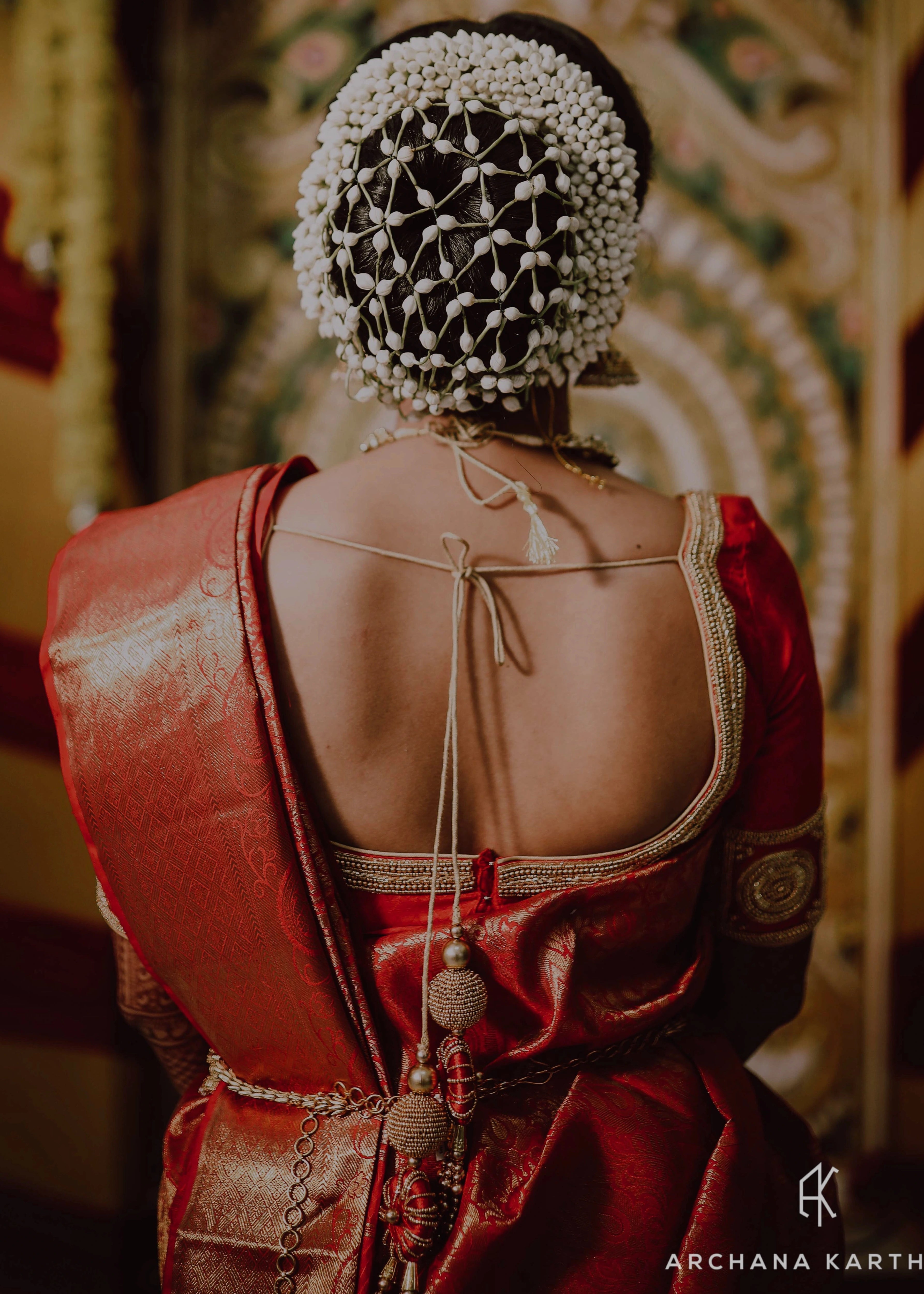 Bride from USA posing in a red silk blouse for her engagement ceremony. Handcrafted intricately with beads, zardozi and sequins by team Archana Karthick.