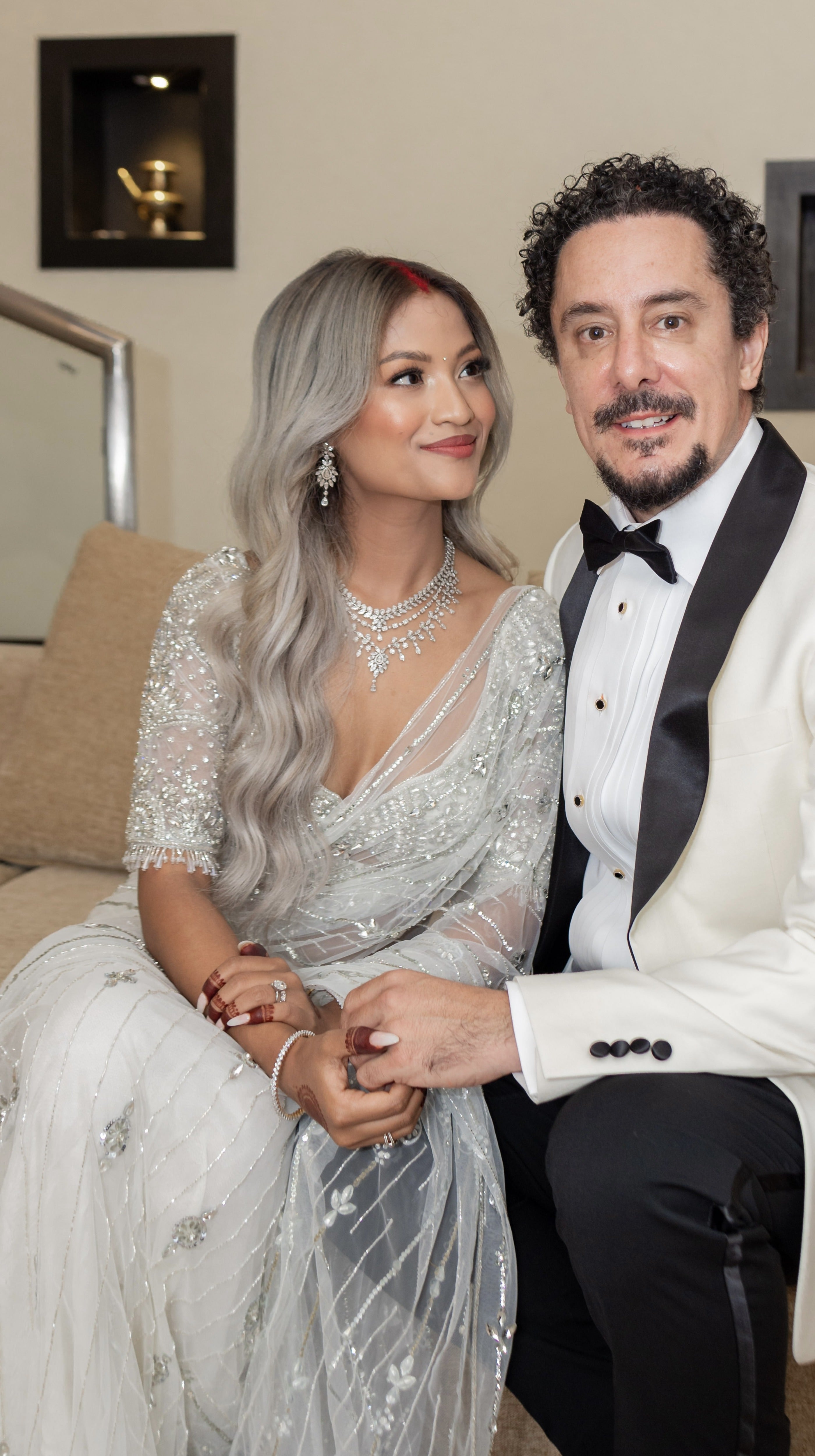 Bride from texas in white net saree for wedding reception in nepal. She looks at the groom lovingly in this closeup shot where we can see the intricate detalings on the blouse. The saree shines with intricate stonework, sequins and cut dana details.