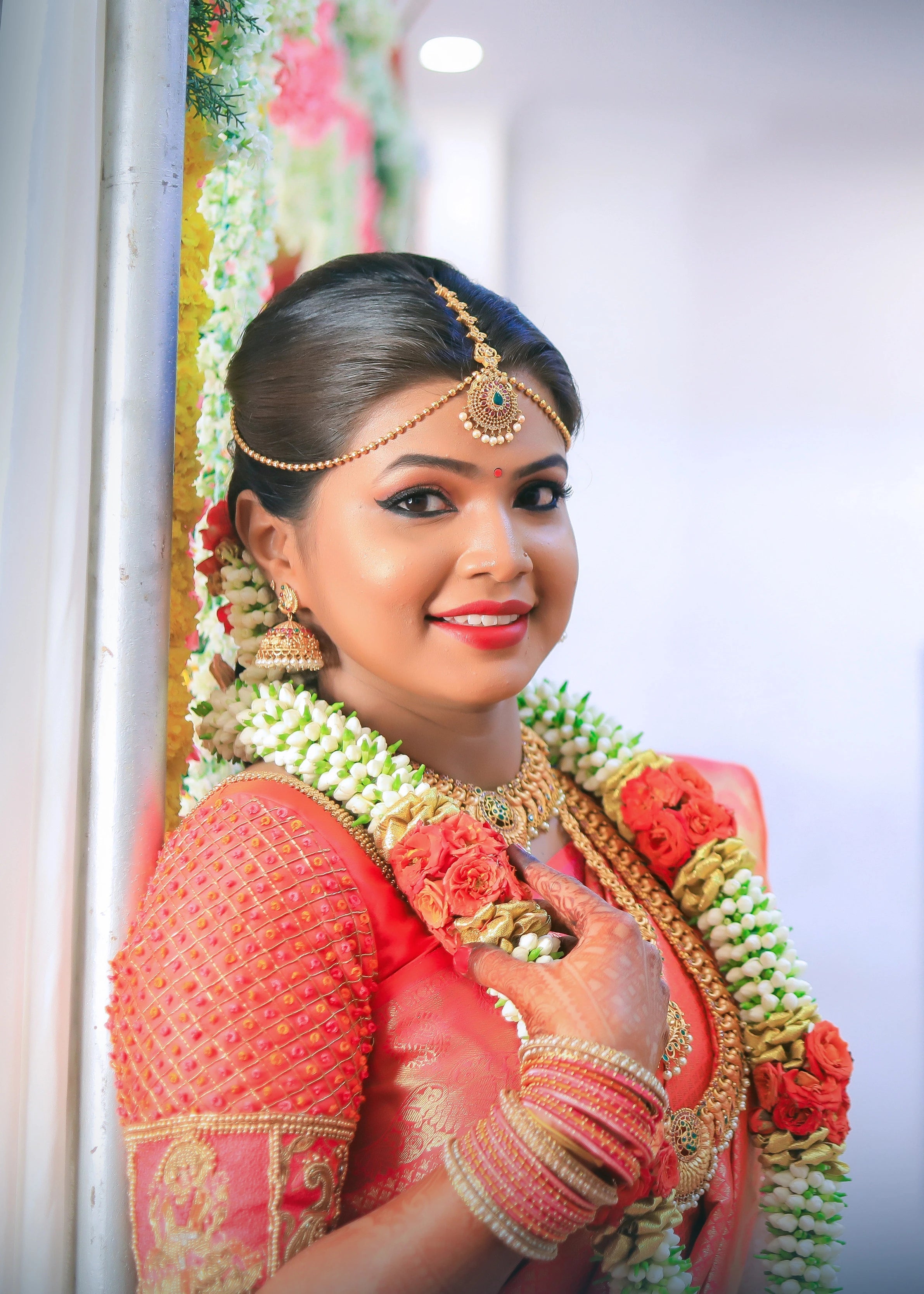 Bride in a handcrafted orange silk blouse designed by Archana Karthick posing for a side profile photo