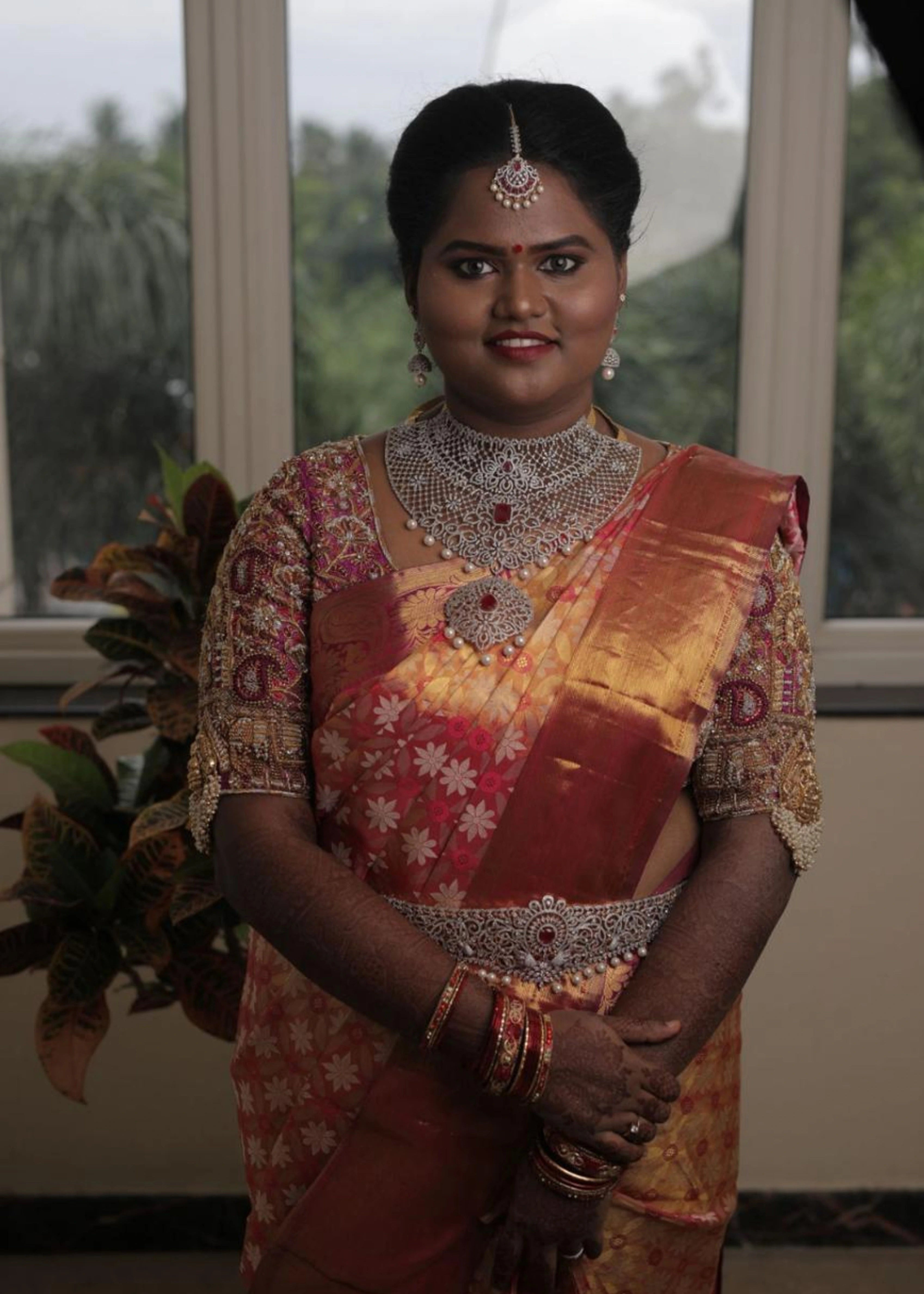 Bride in a handcrafted palanquin concept magenta pink silk blouse with zardozi, kemp stones, pearls and resham knot work and goddess pendants on each sleeve. Designed by Archana Karthick
