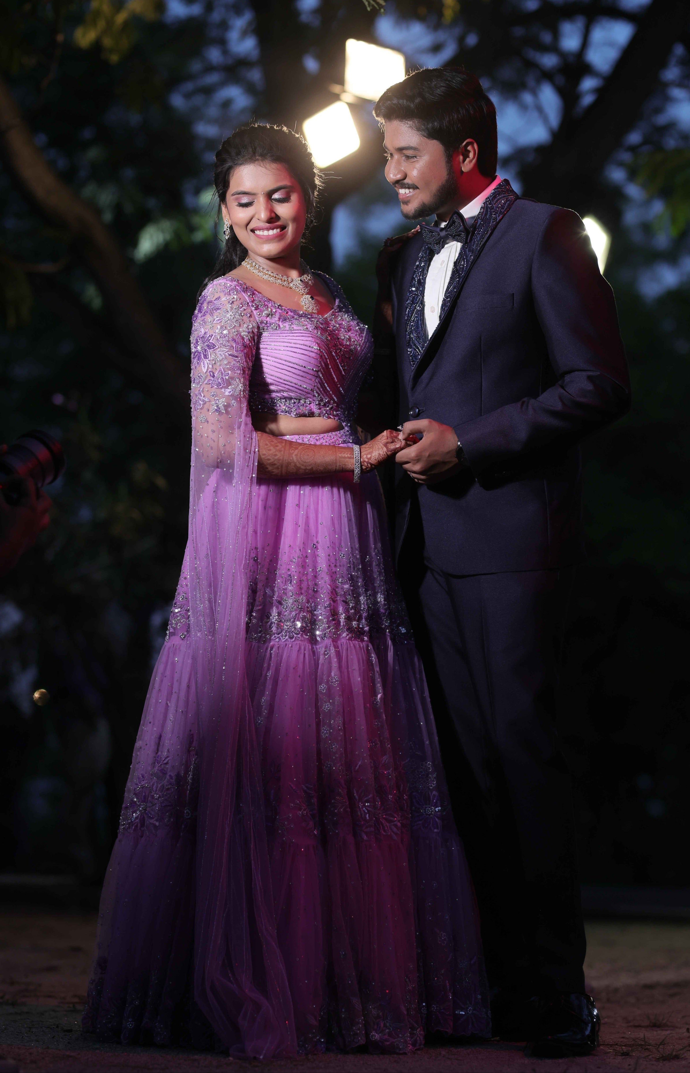 Bride in a lavender handcrafted lehenga with trail sleeves and groom in a bespoke navy two piece suit with handcrafted lapels and bow tie for their reception. The outfits for both the bride and groom is designed by Archana Karthick.