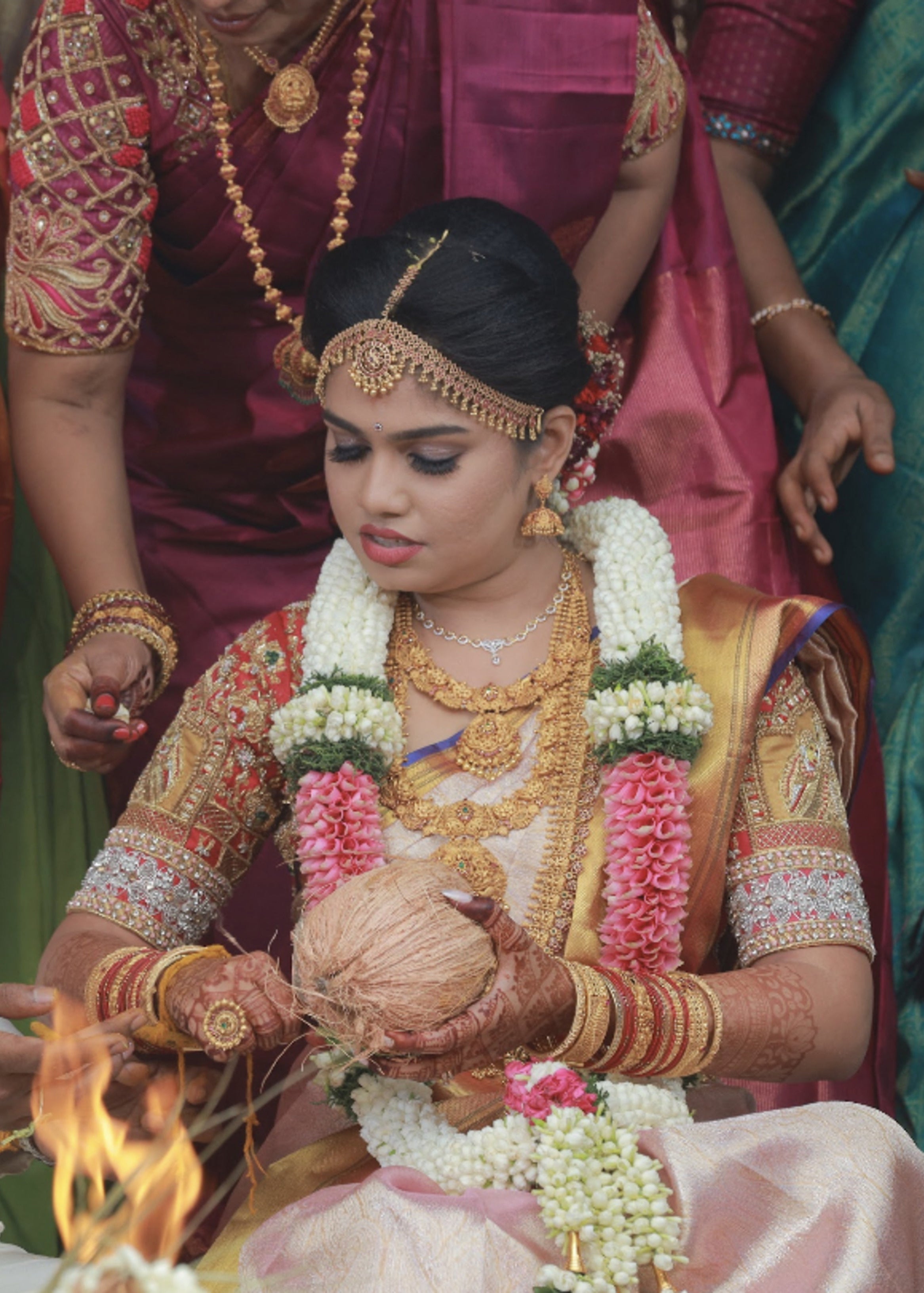 Bride in a red silk blouse handcrafted by team Archana Karthick.