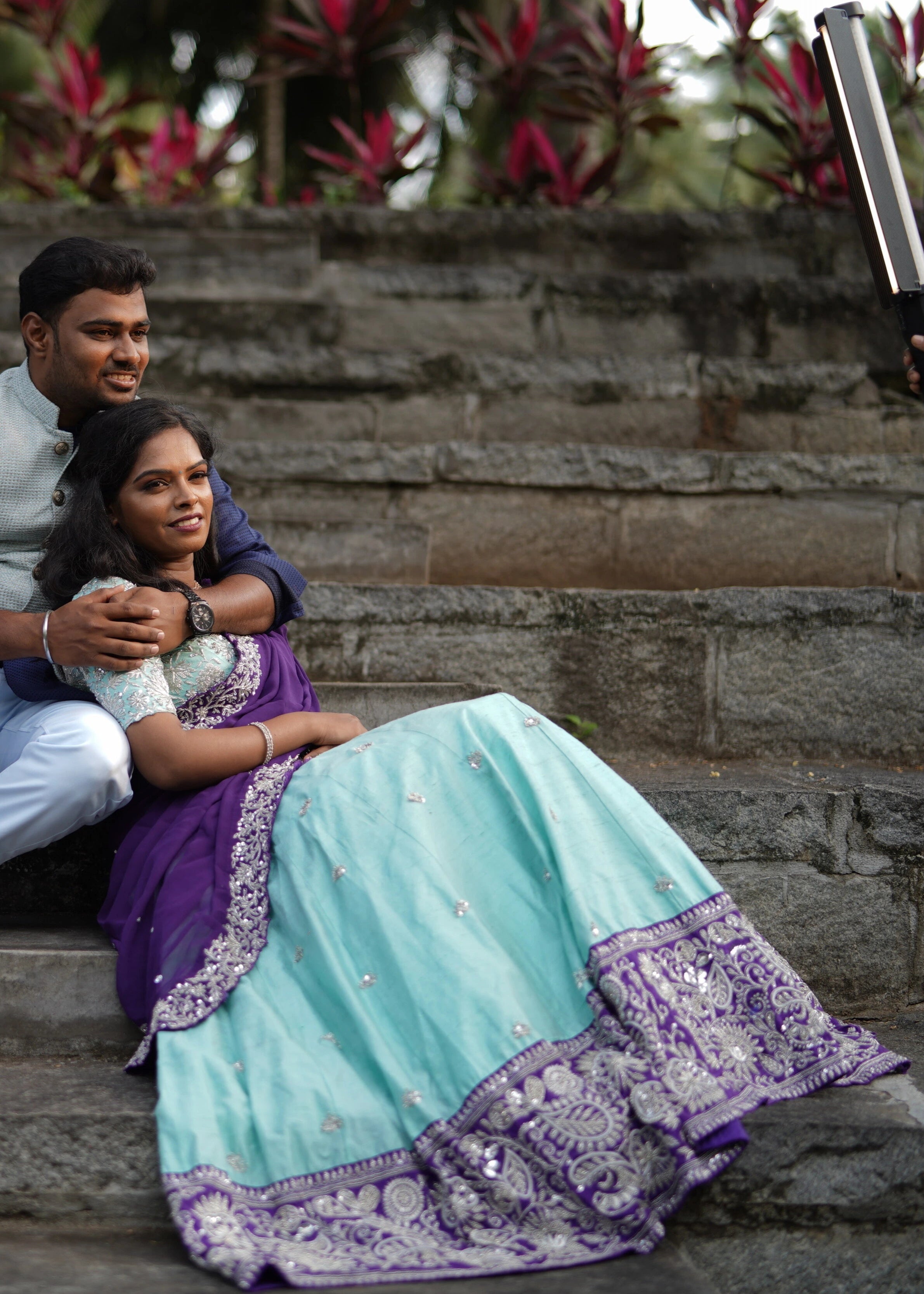 Bride in an embrace in blue and purple rawsilk lehenga designed by Archana Karthick