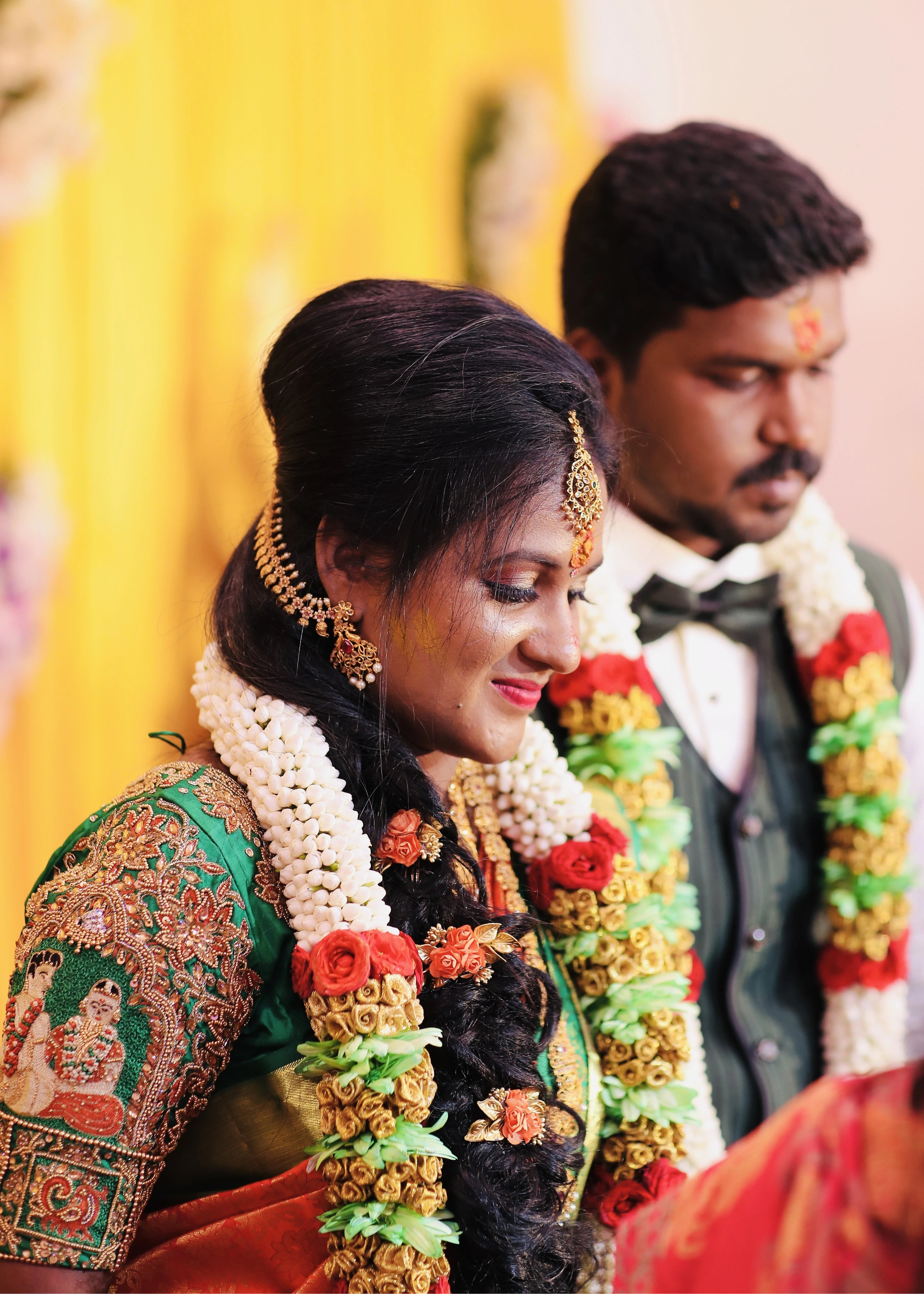 Bride in handcrafted concept silk blouse in green depicts the bride and groom on the sleeves with zardozi, beads, resham, sequins and peacock motifs on sleeves. Designed by Archana Karthick