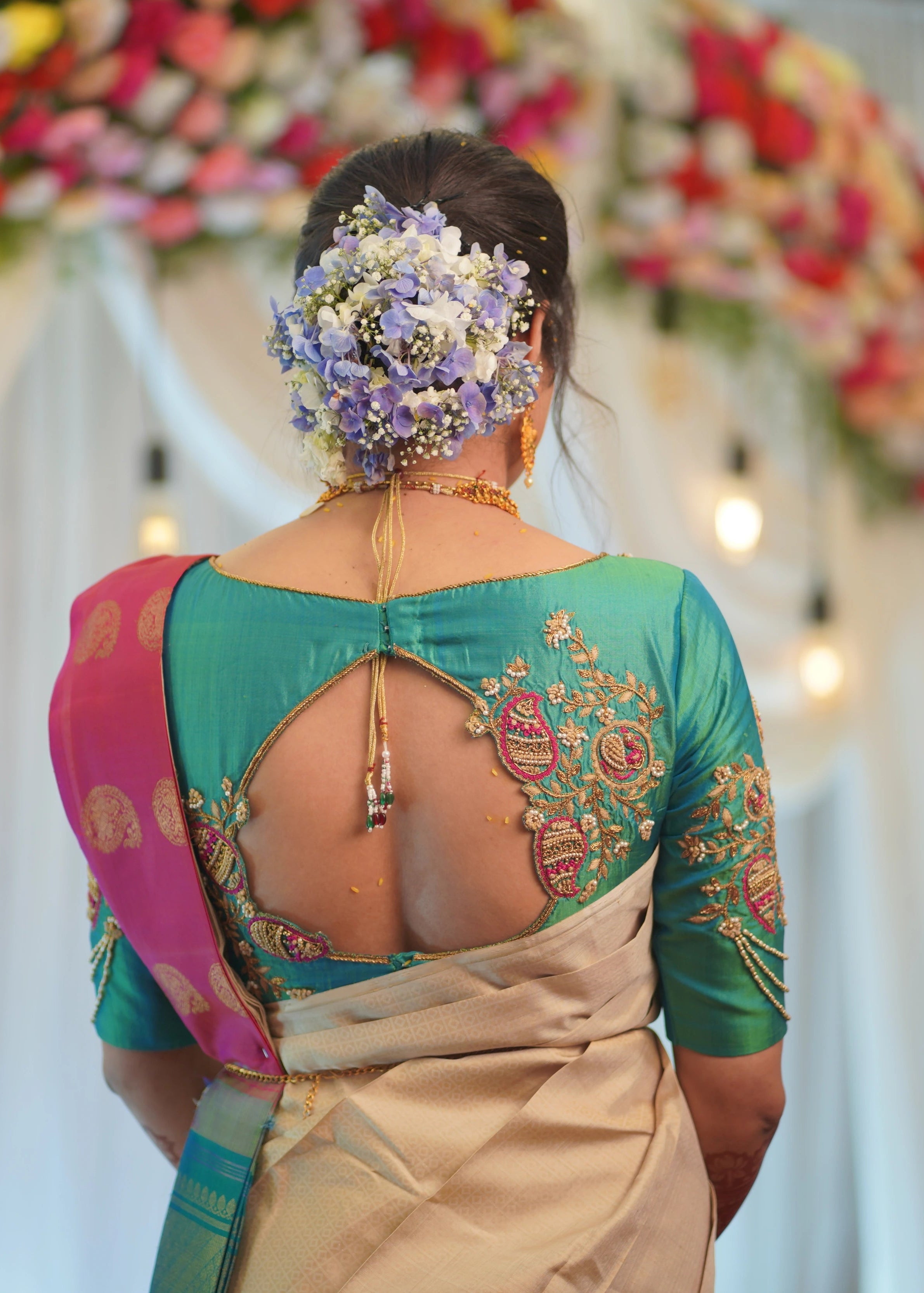 Bride in handcrafted teal silk blouse with paisley motifs designed by Archana Karthick posing for back blouse design