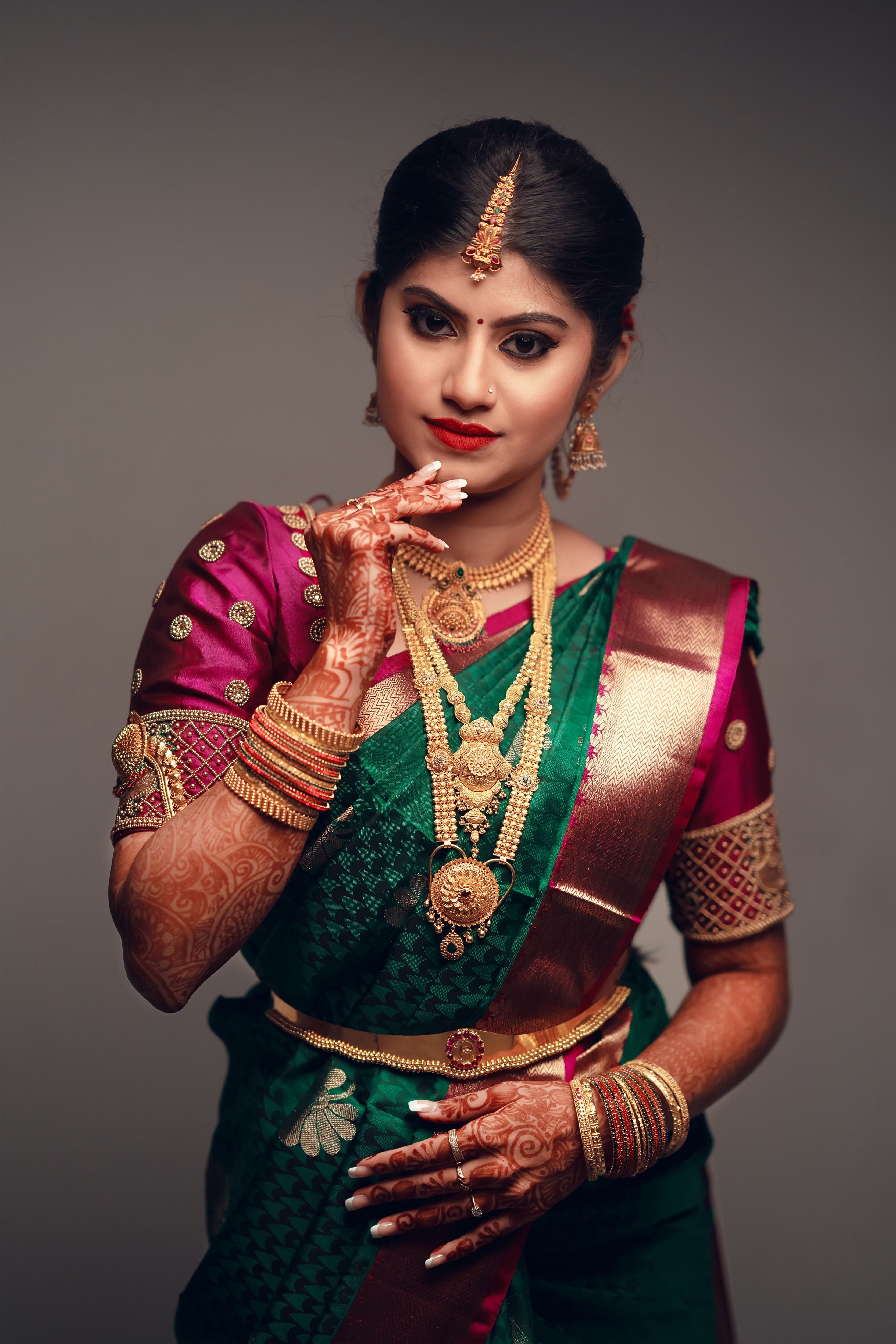 Bride Vandita from Bagalore is seen here in our silk aubergine colored blouse.This is designed for her engagement. Resham, zardozi, beads and mirror work techniques used on the blouse. The right arm is touching her chin which shows part of her right sleeve.