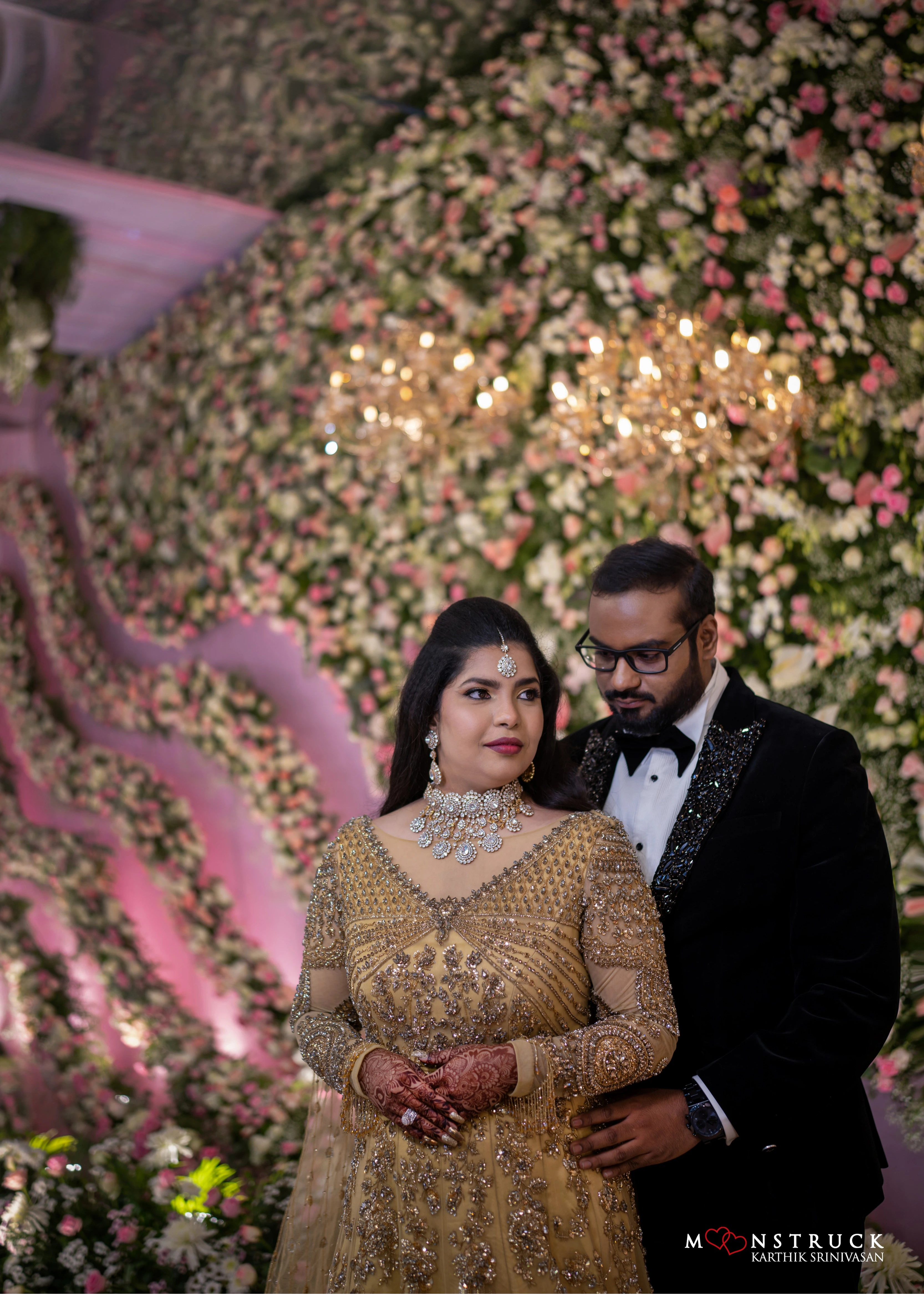 Bride looking away with groom in a gold gown in tulle designed by Archana Karthick and handcrafted with rhinestones and cut dana with floral and geometric motifs.