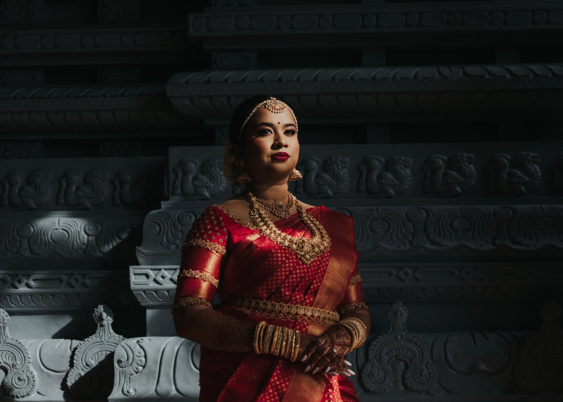 Bride looking far in a handcrafted palanquin concept red silk blouse features zardozi and beads. Designed by Archana Karthick.