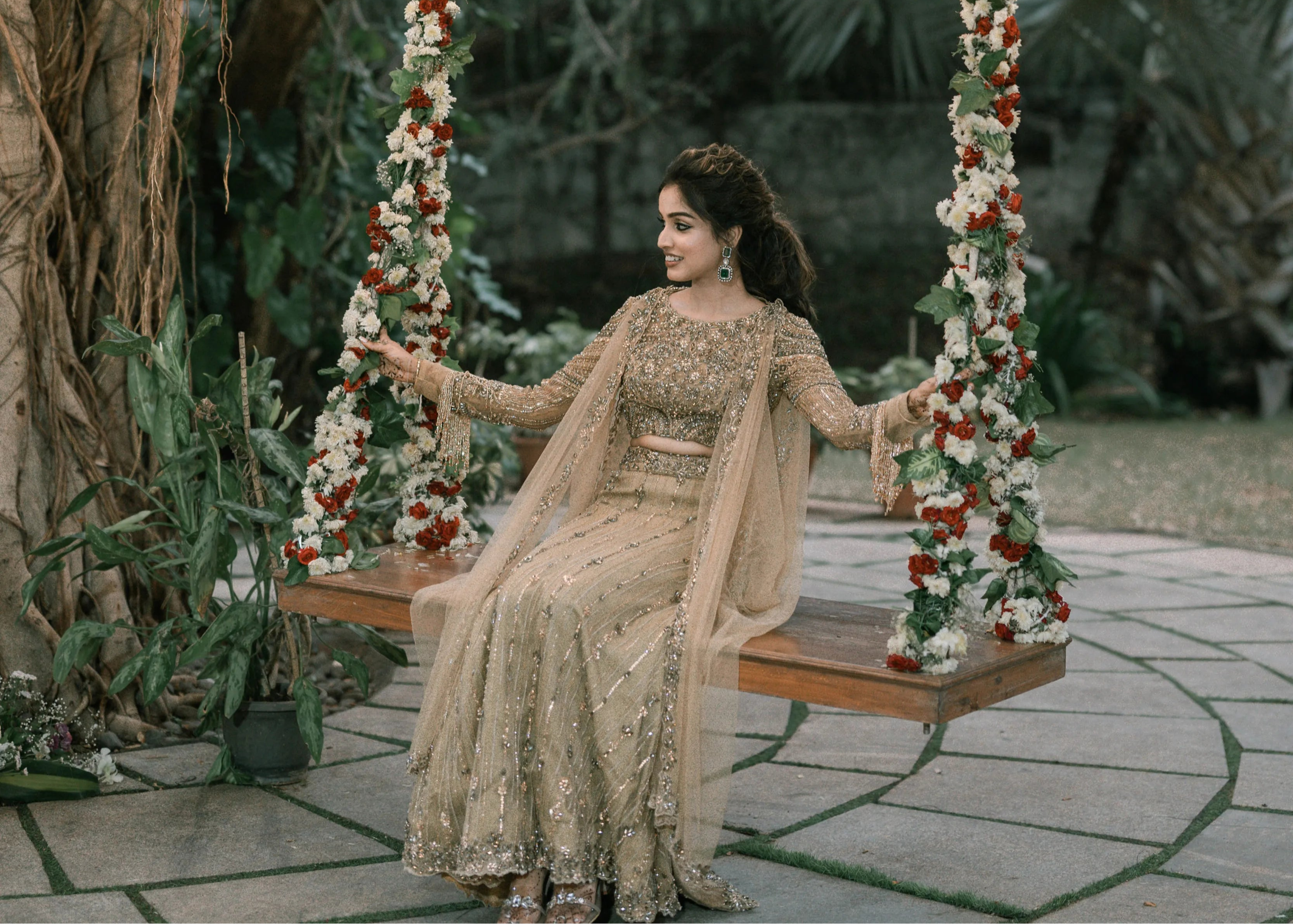 Bride on a swing in a concept gold lehenga in tulle designed by Archana Karthick is handcrafted intricately with rhinestones, crystal beads, cutdanas and sequins.