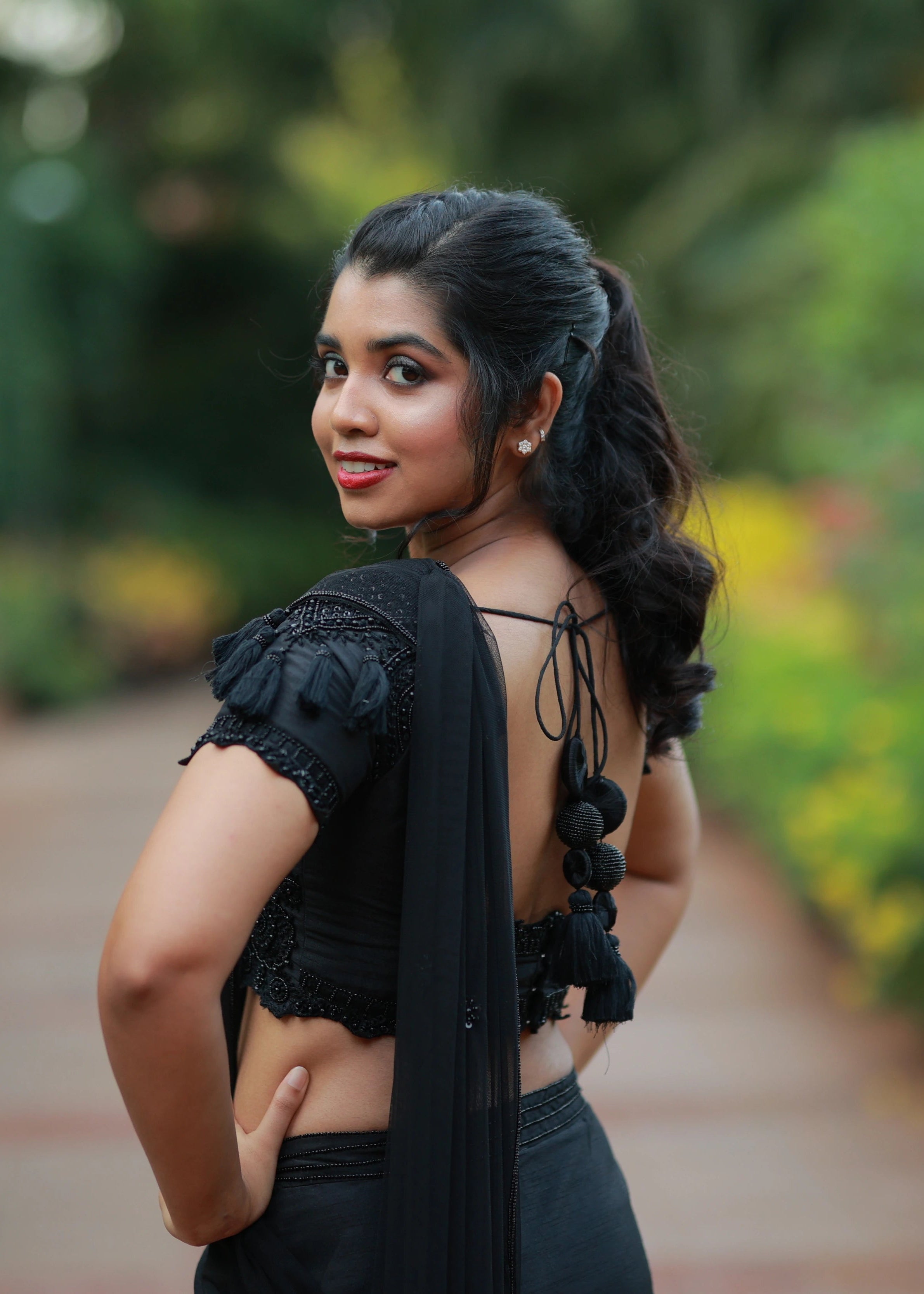 Bride posing for back design in a black mermaid drape handcrafted with beads, cut dana, sequins, resham and handmade tassels to finish the look. Designed by Archana Karthick.