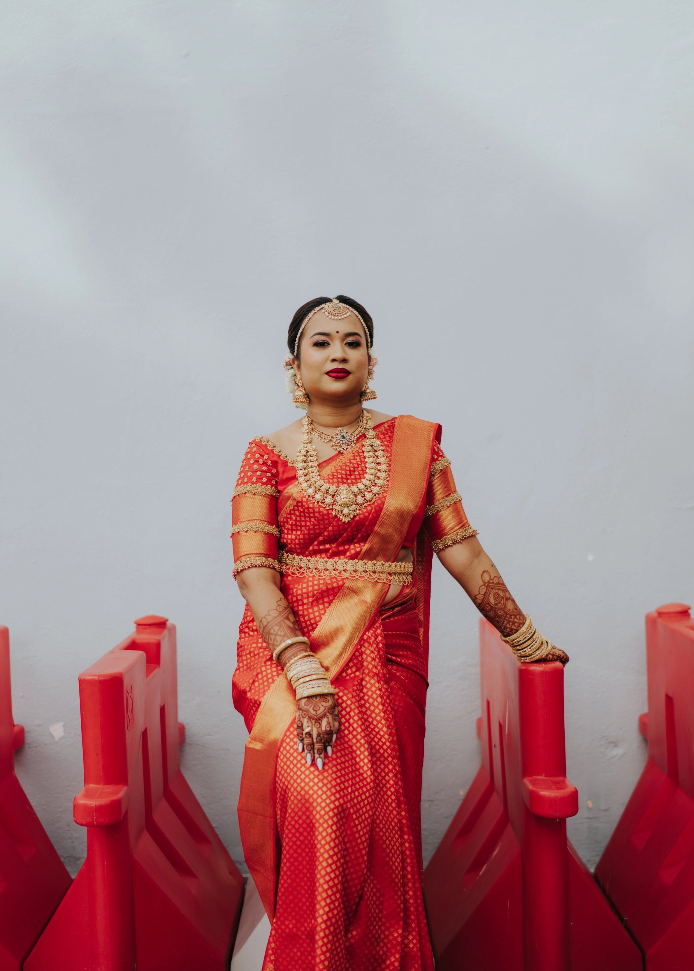 Bride posing in a handcrafted palanquin concept red silk blouse features zardozi and beads. Designed by Archana Karthick.