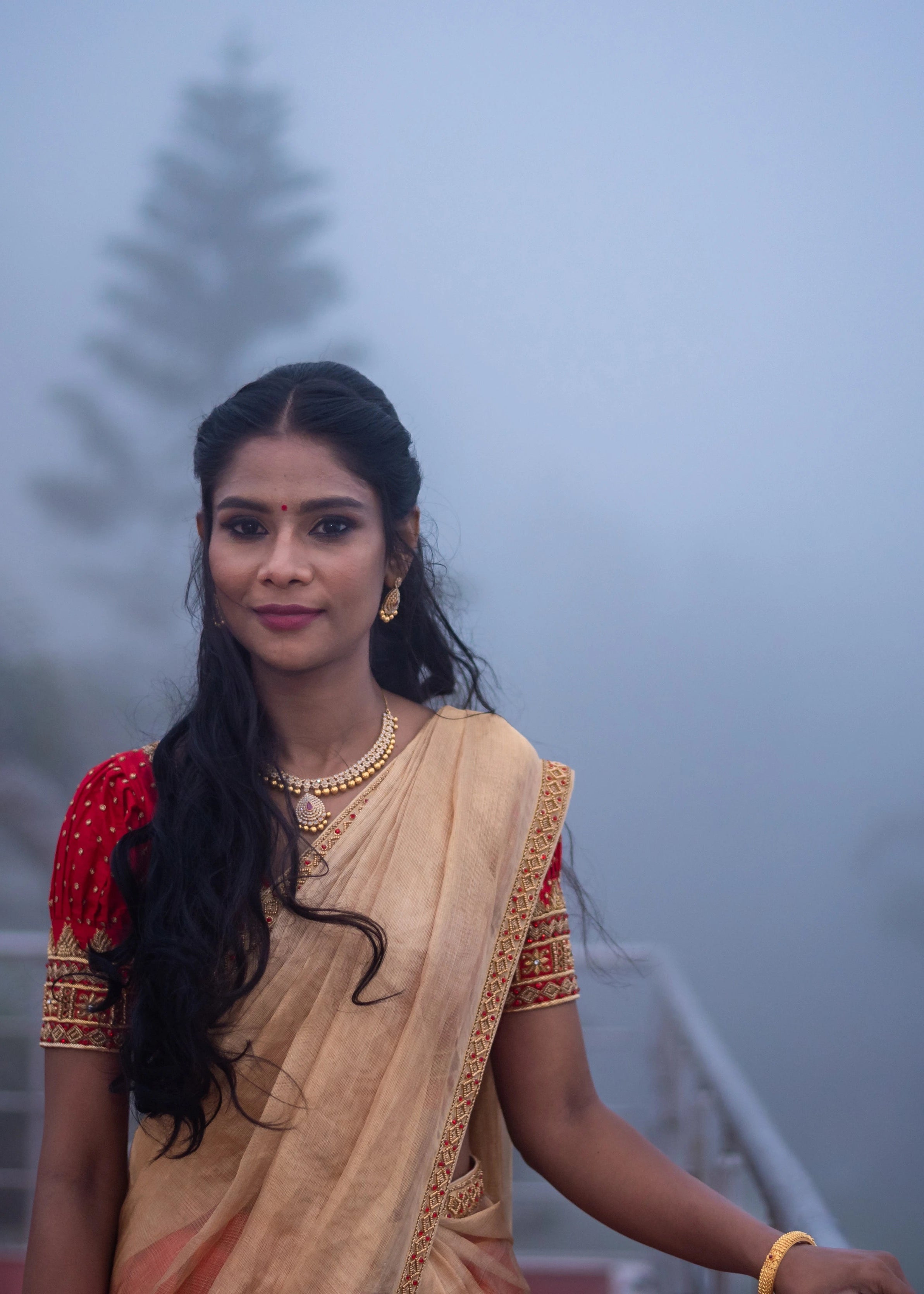 Bride posing in a handcrafted red silk half saree with katori cut blouse has intricate zardozi and stone work.