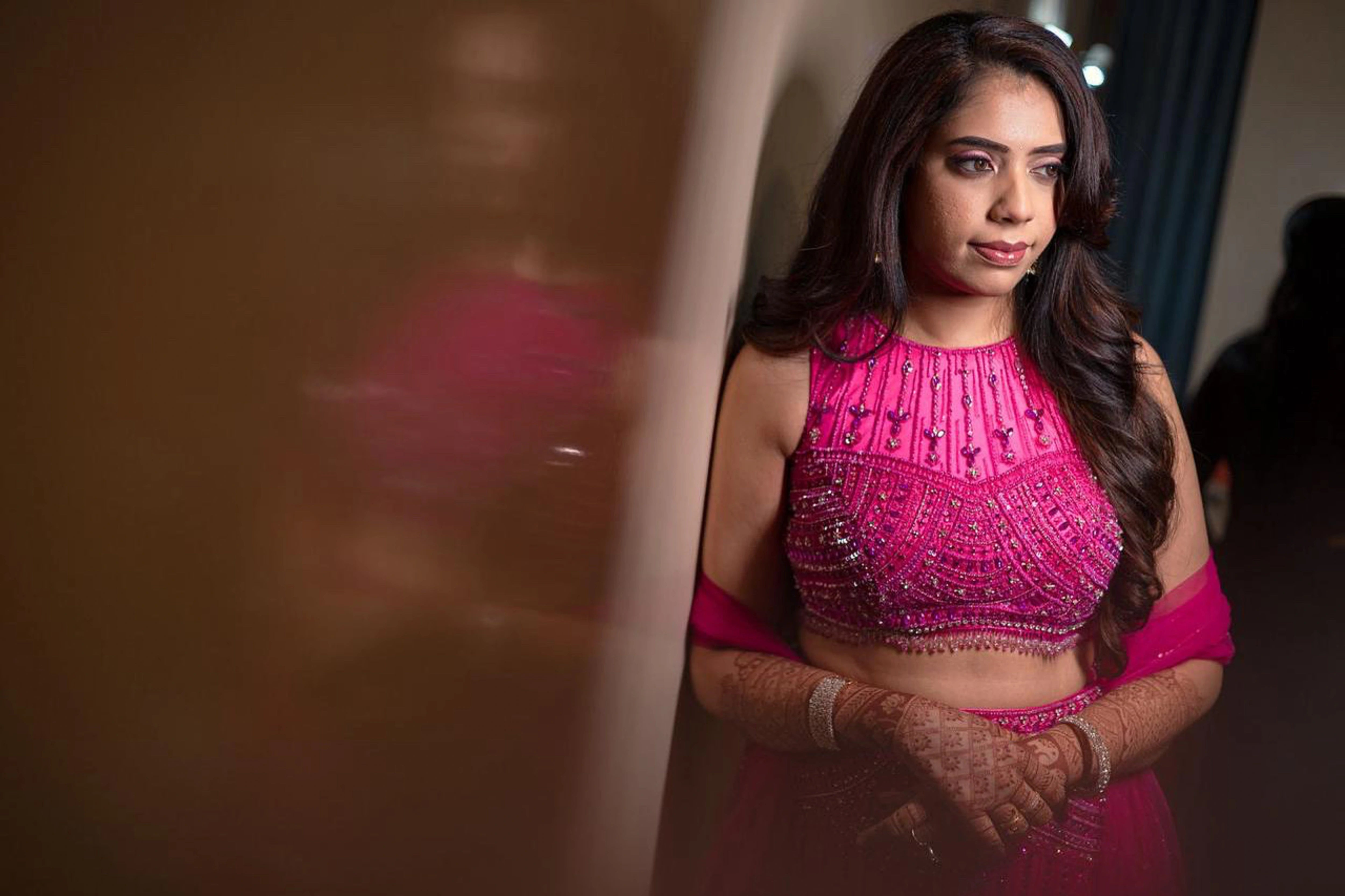 Bride posing in a pink tulle mermaid lehenga, intricately handcrafted by team Archana Karthick