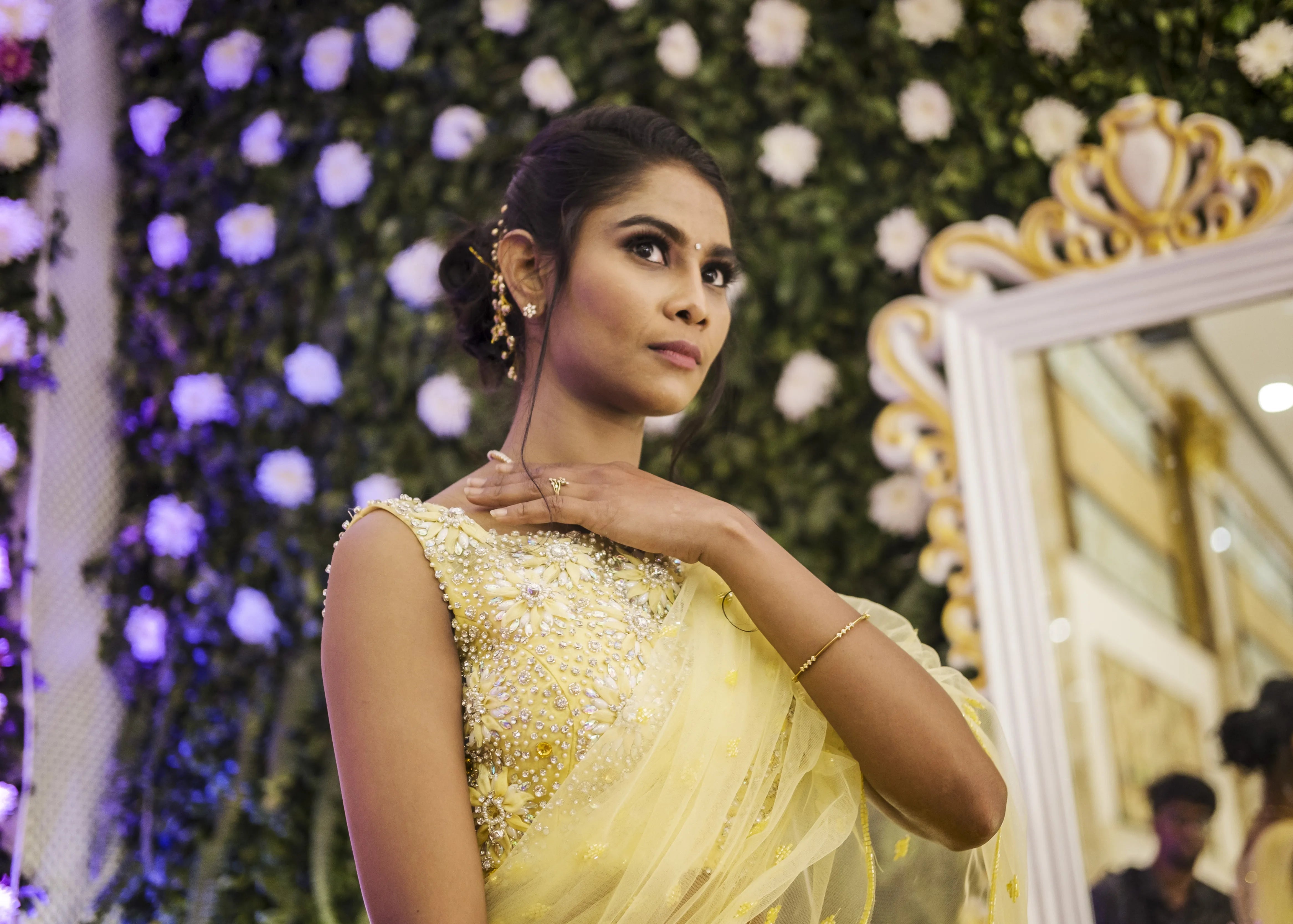 Bride posing on stage with groom in handcrafted yellow mermaid lehenga embellished with cut dana, pearls, rhinestones and handmade 3D flowers.