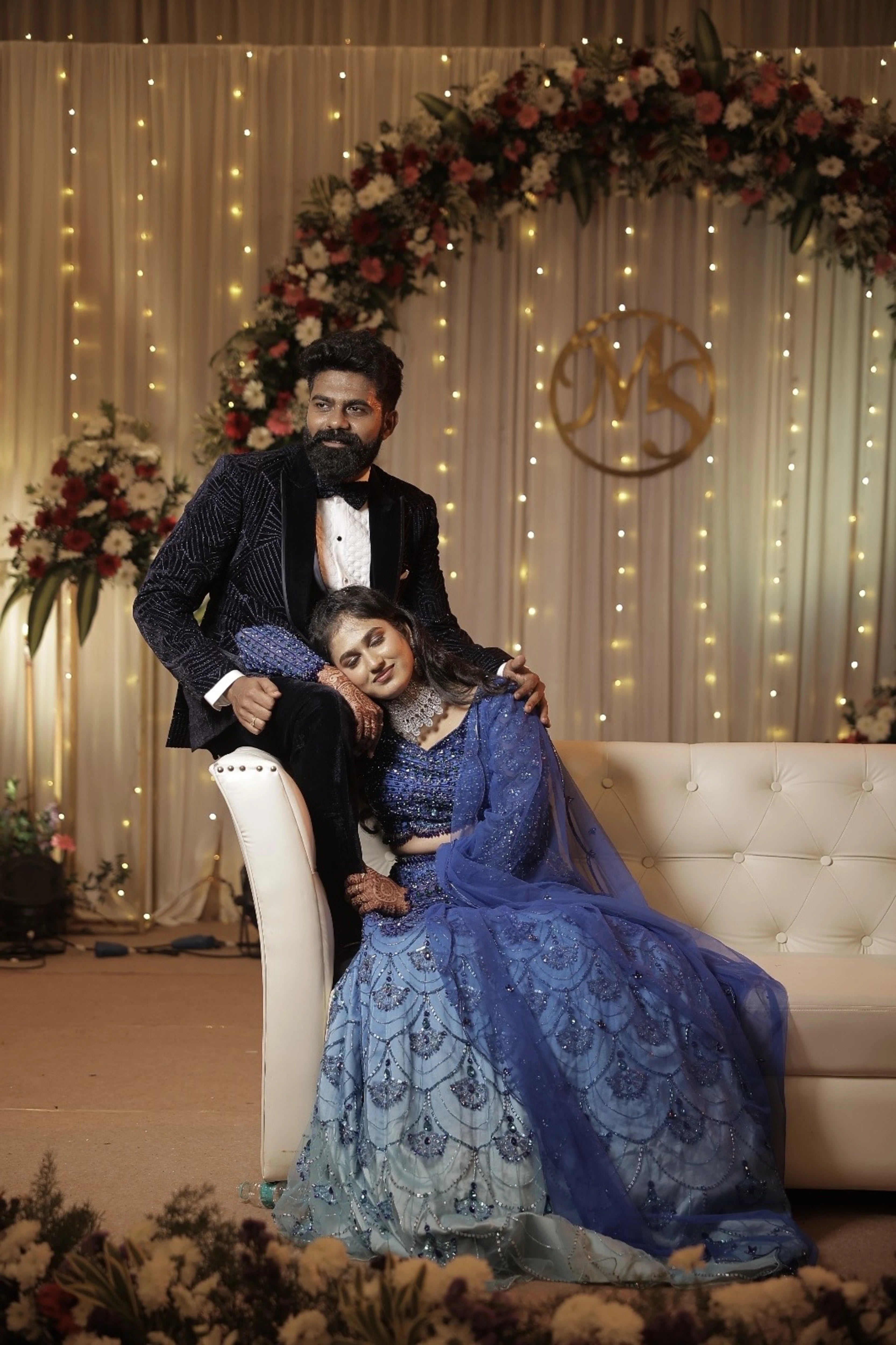 Bride Monishka posing with groom in a peacock themed blue ombre tulle lehenga, handcrafted with sequins, cutdana, rhinestones and feathers by team Archana Karthick.