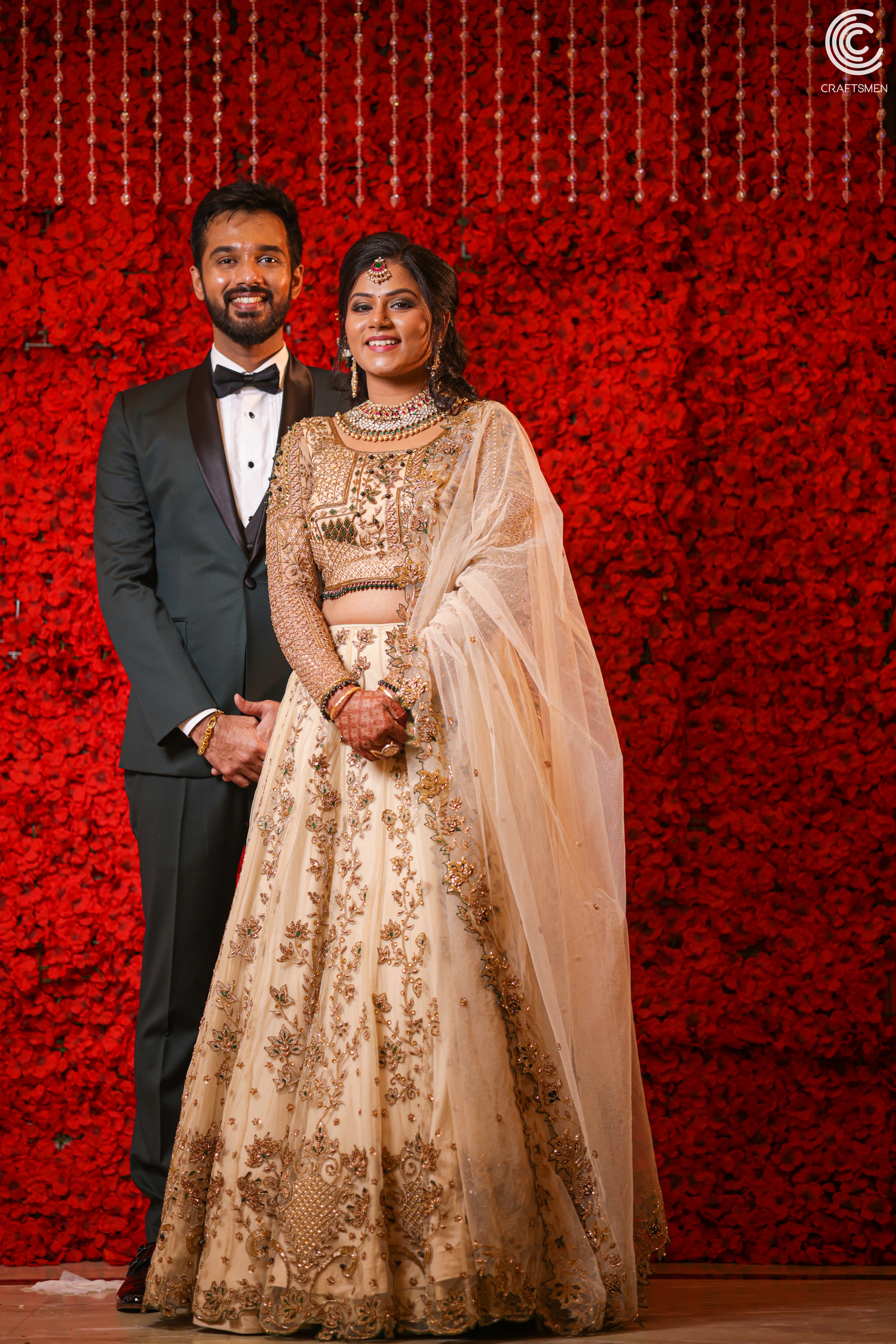 Bride posing with groom in an ivory lehenga in tulle with cut worked dupatta and handcrafted intricately with stones, zardozi, reshams knot work, beads and cutdanas. Designed by Archana Karthick