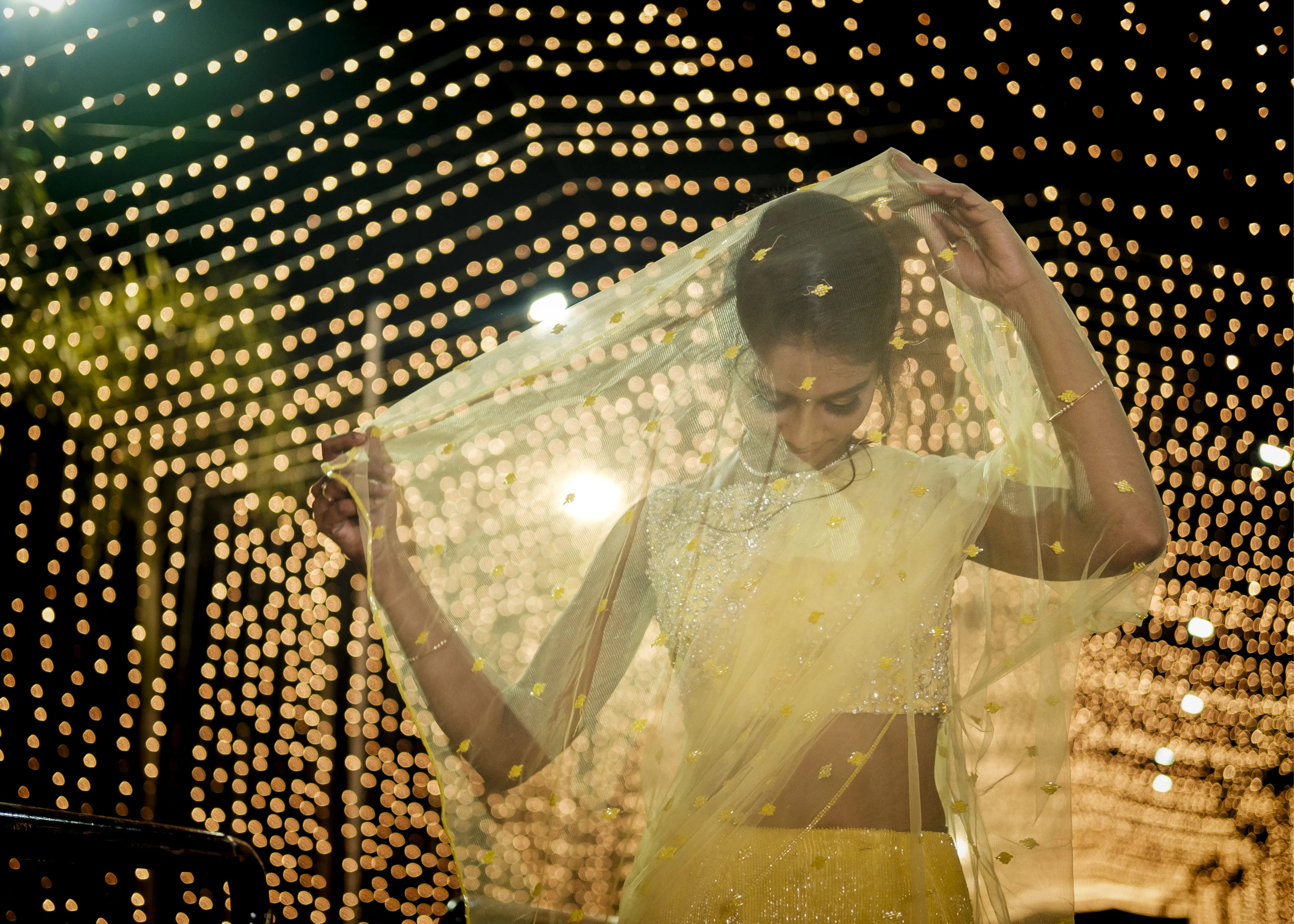 Bride posing with veil for photoshoot in handcrafted yellow mermaid lehenga embellished with cut dana, pearls, rhinestones and handmade 3D flowers.