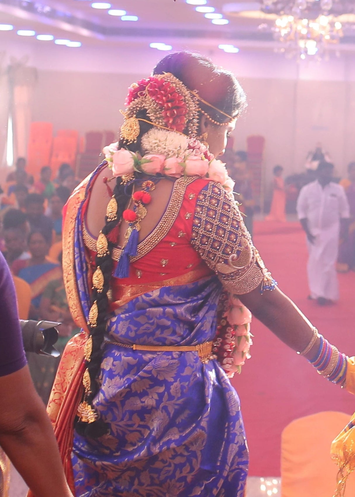 Bride showcasing black bouse design in a concept peacock blouse in blue and red silk, handcrafted with zardozi, beads, resham knot work and goddess pendant on sleeves.