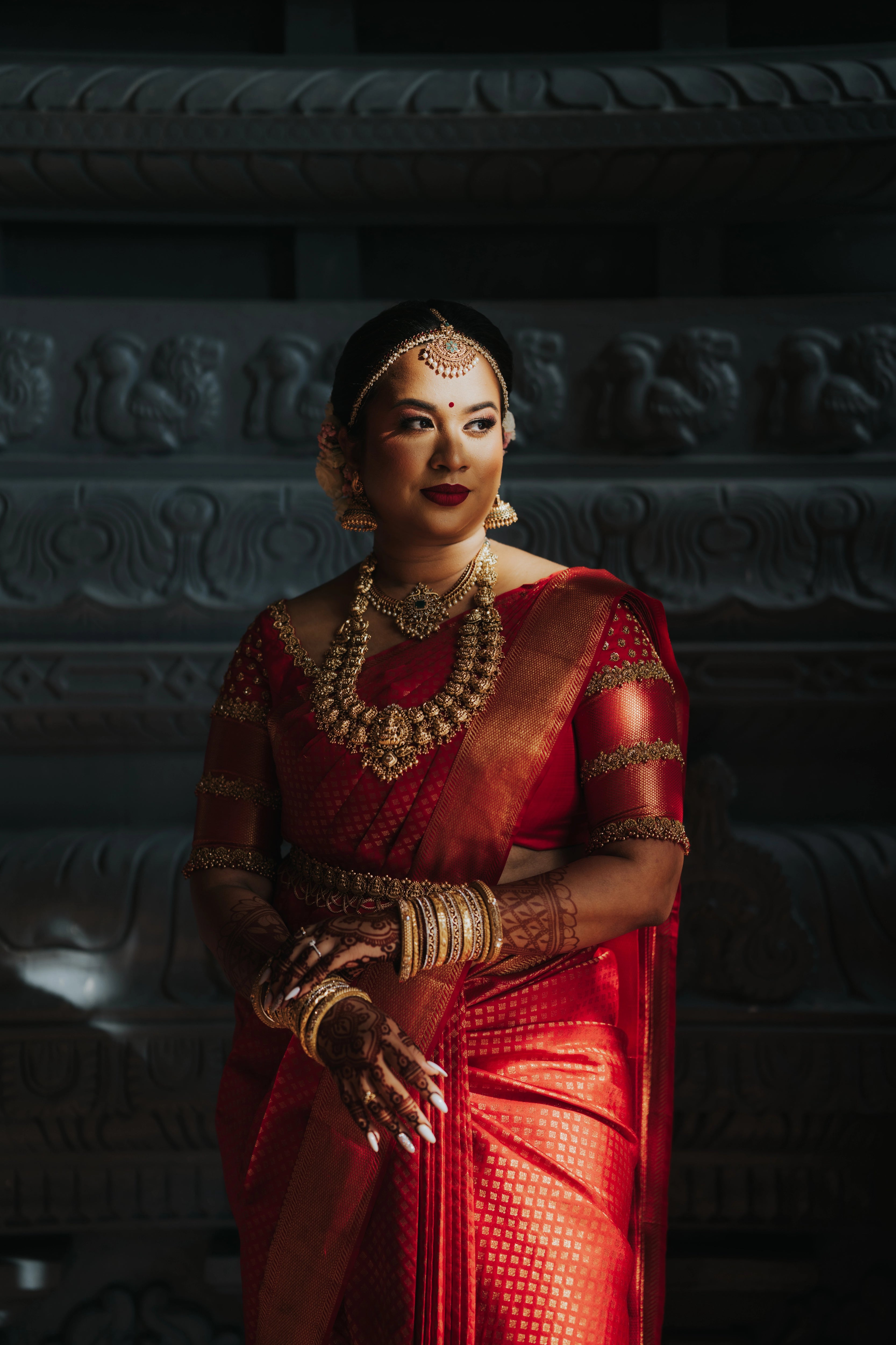 Bride showcasing front blouse design in a handcrafted palanquin concept red silk blouse features zardozi and beads. Designed by Archana Karthick.