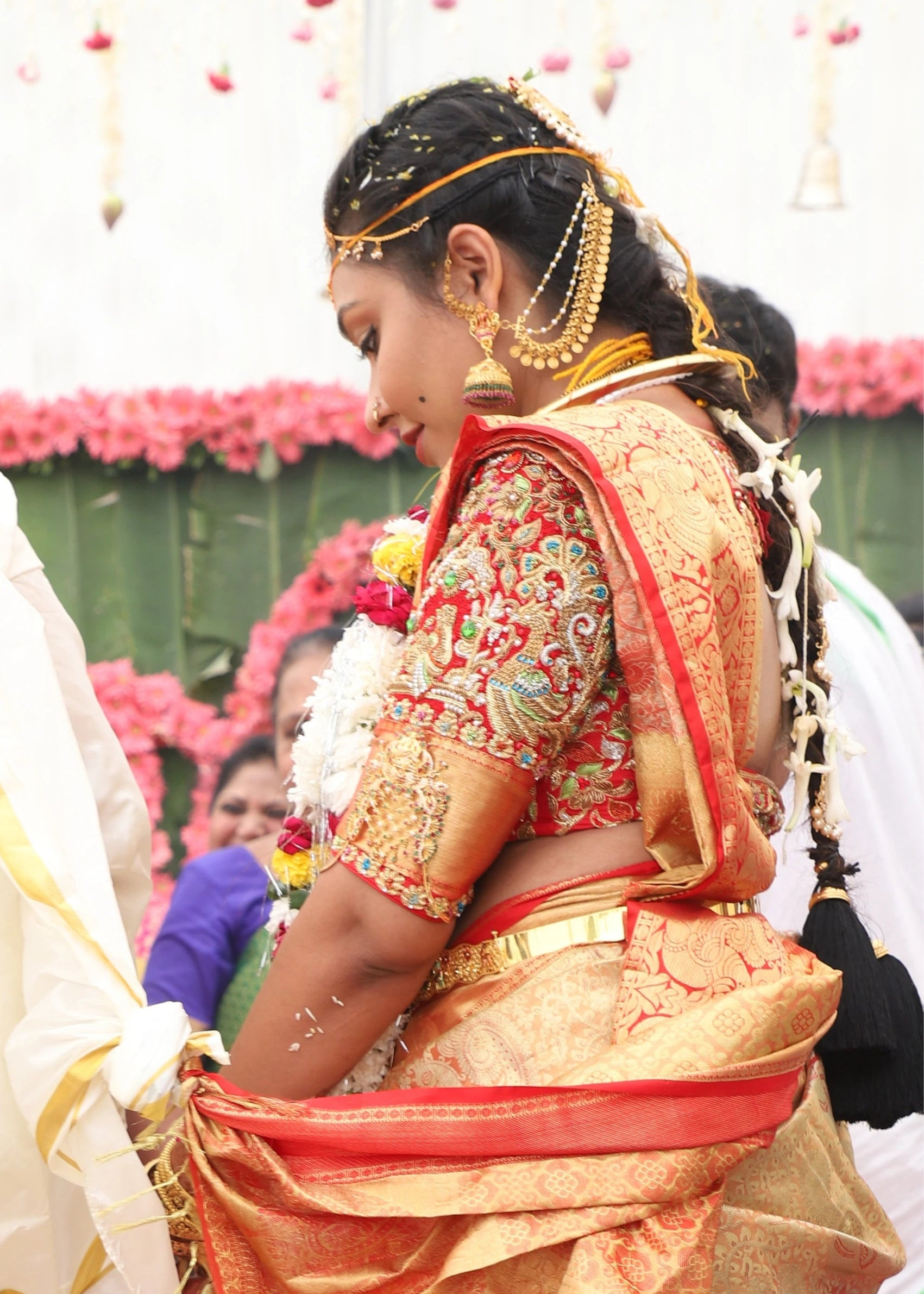Bride smiling in a bride and groom concept red silk blouse is a handcrafted with zardozi, rhinestones, pearls and beads. Designed by Archana Karthick