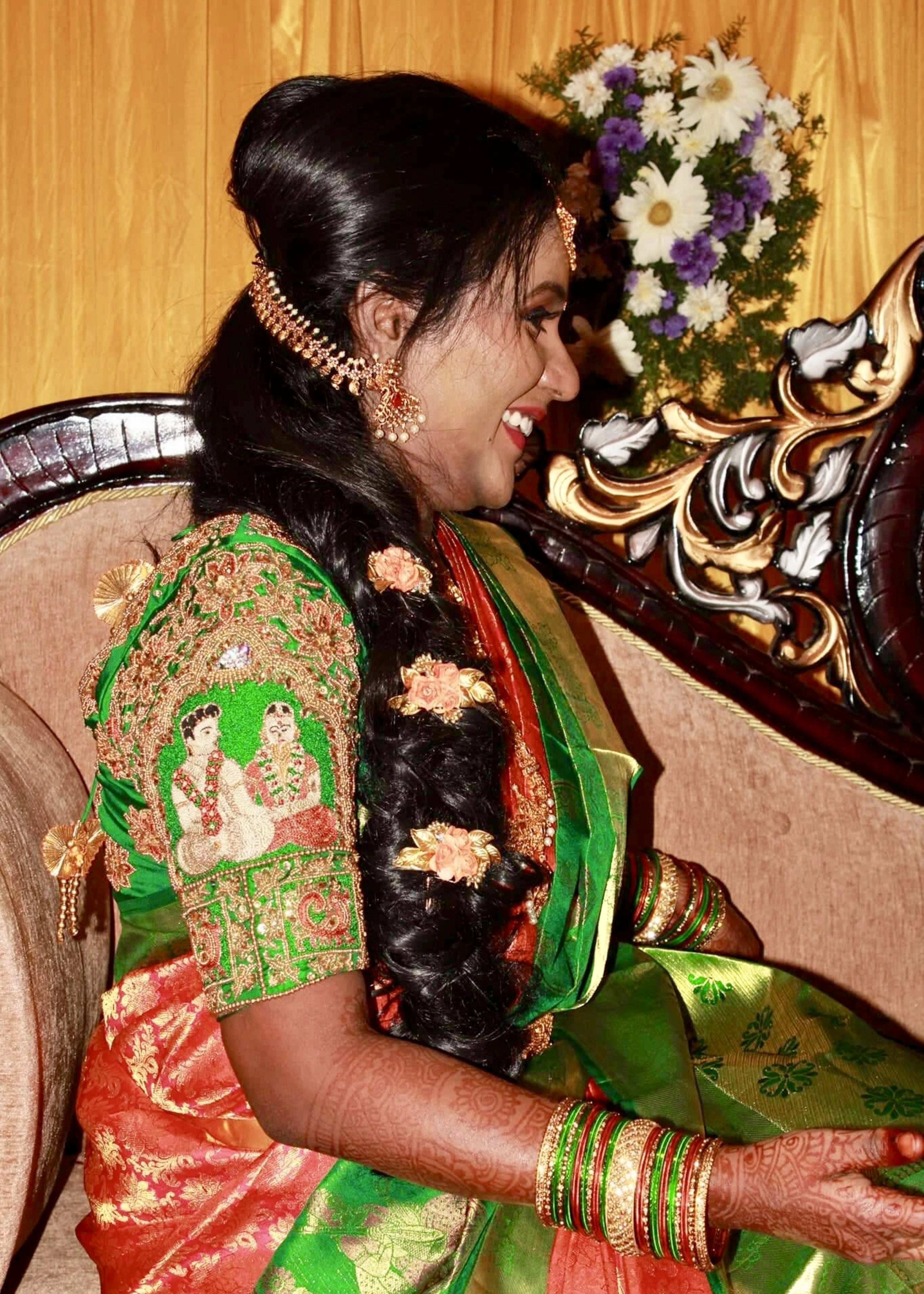 Bride smiling in handcrafted concept silk blouse in green depicts the bride and groom on the sleeves with zardozi, beads, resham, sequins and peacock motifs on sleeves. Designed by Archana Karthick
