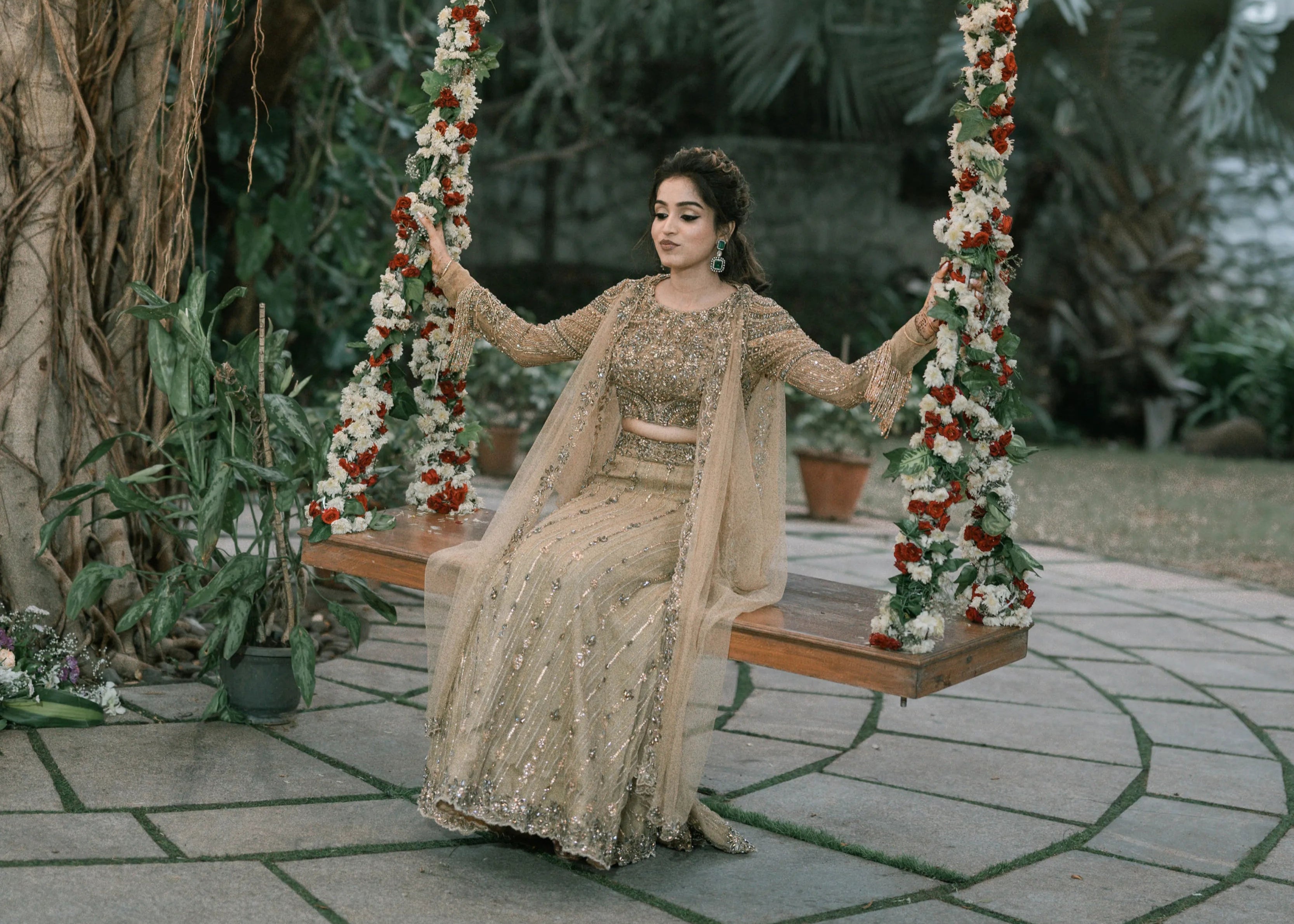 Bride smiling on a swing in a concept gold lehenga in tulle designed by Archana Karthick is handcrafted intricately with rhinestones, crystal beads, cutdanas and sequins.