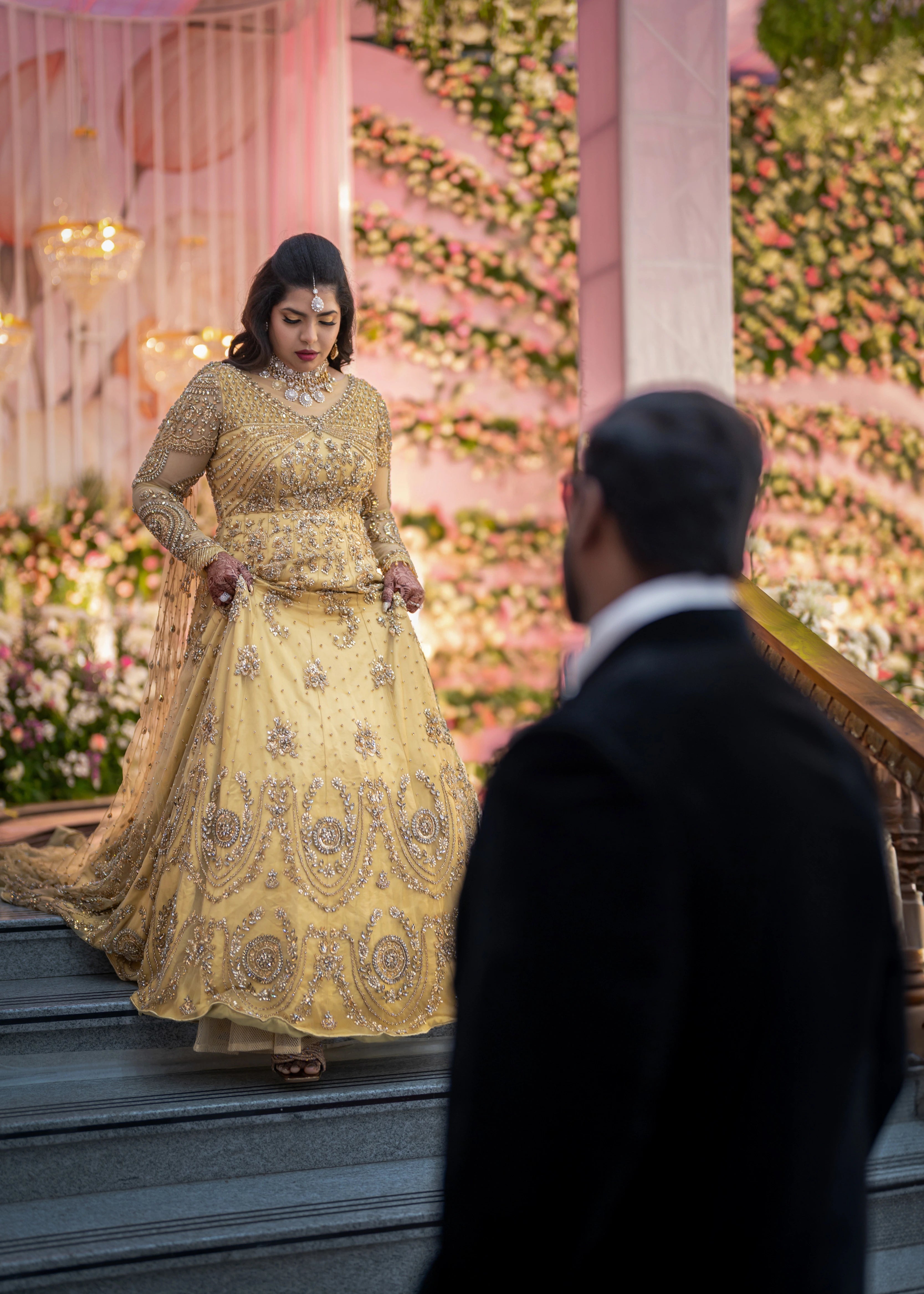 Bride walking down in a gold gown in tulle designed by Archana Karthick and handcrafted with rhinestones and cut dana with floral and geometric motifs.