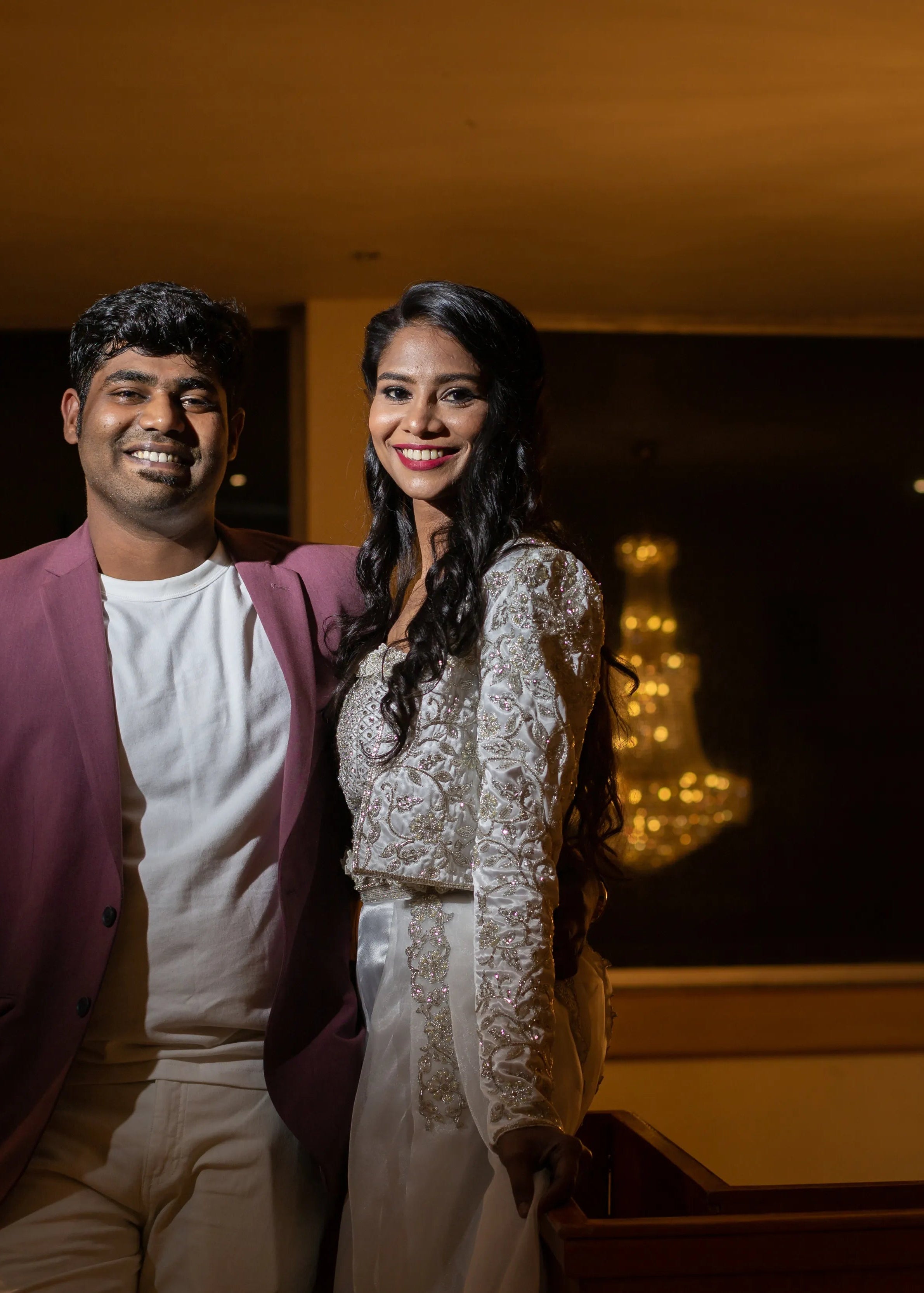 Bride with the groom at her party in handcrafted silver satin and organza corset outfit embellished with cut dana, pearls, stones and sequins. Designed by Archana Karthick