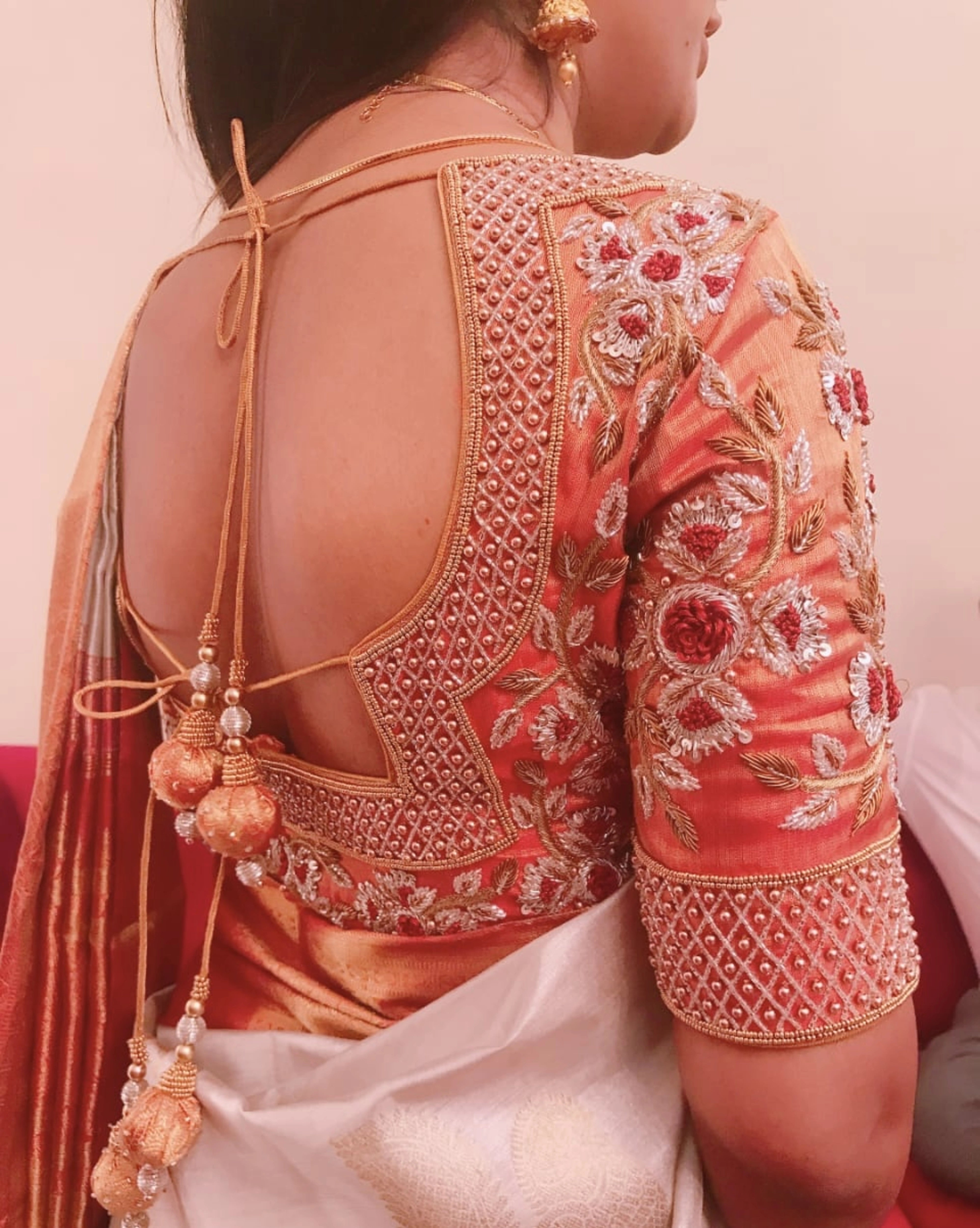 Bridesmaid Dr Nivetha from Bangalore, posing in an orange silk blouse, handcrafted by team Archana Karthick.