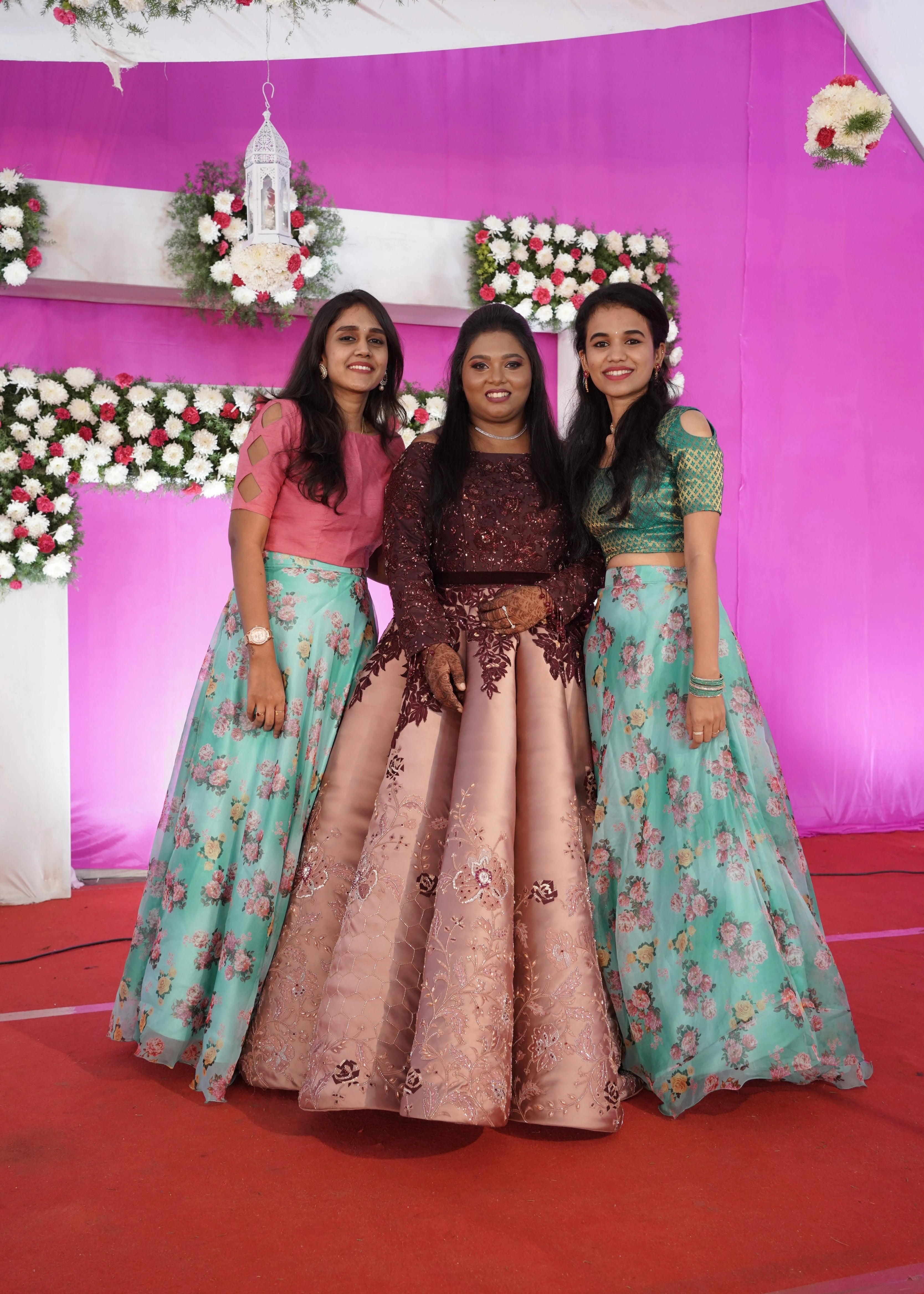 Bridesmaid Ramadevi in a maroon and peach cream satin panelled gown, intricately handcrafted with multicoloured cutdana, resham and stones.