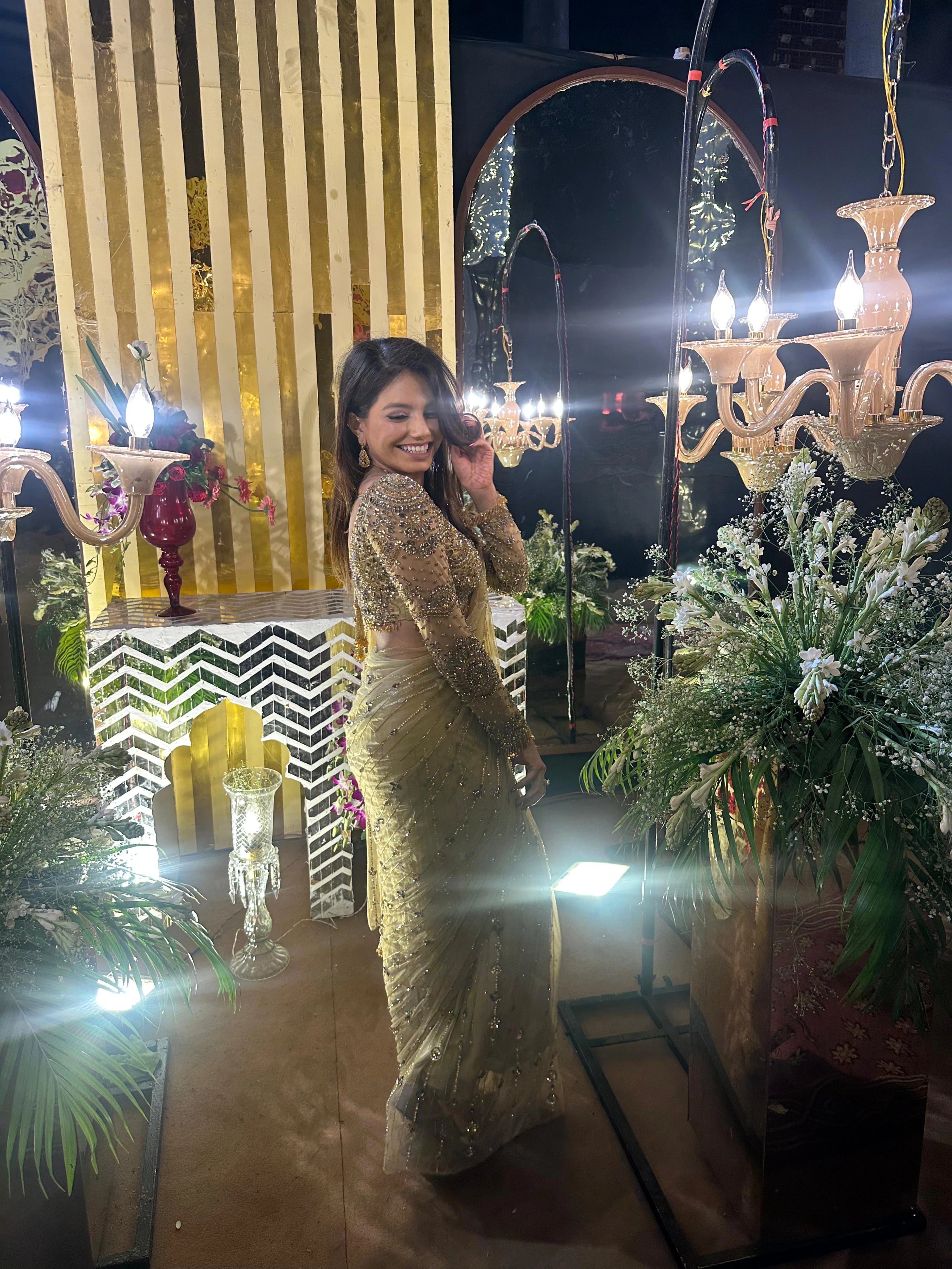 Bridesmaid Vidushi from Jamshedpur, posing sideways in a golden tulle saree handcrafted by team Archana Karthick.
