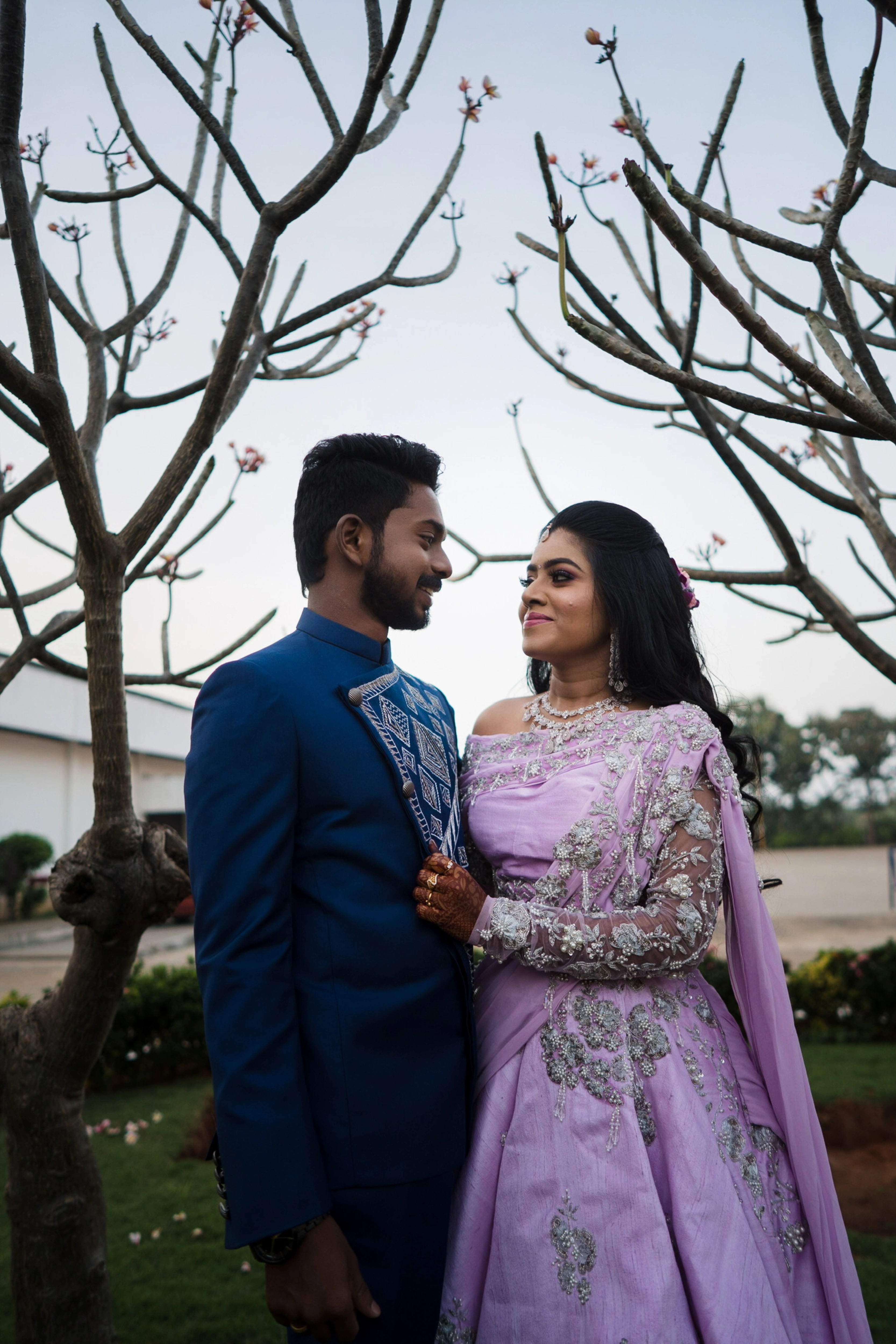 Couple in a lilac raw silk lehenga and blue indo-western bandhgala handcrafted by team Archana Karthick.