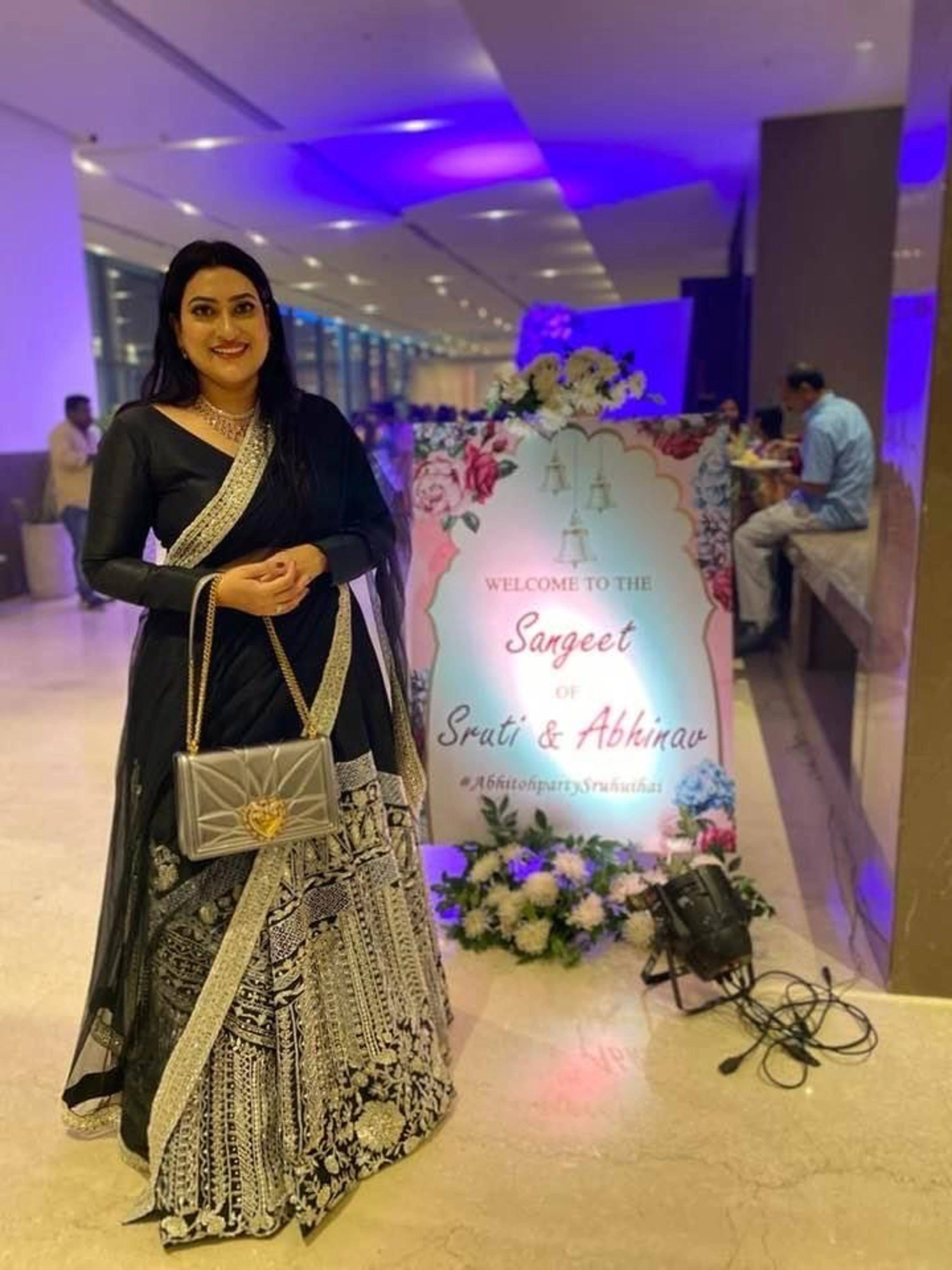 Dr Priya from USA, smiling in a black and silver raw silk lehenga, handcrafted by team Archana Karthick.