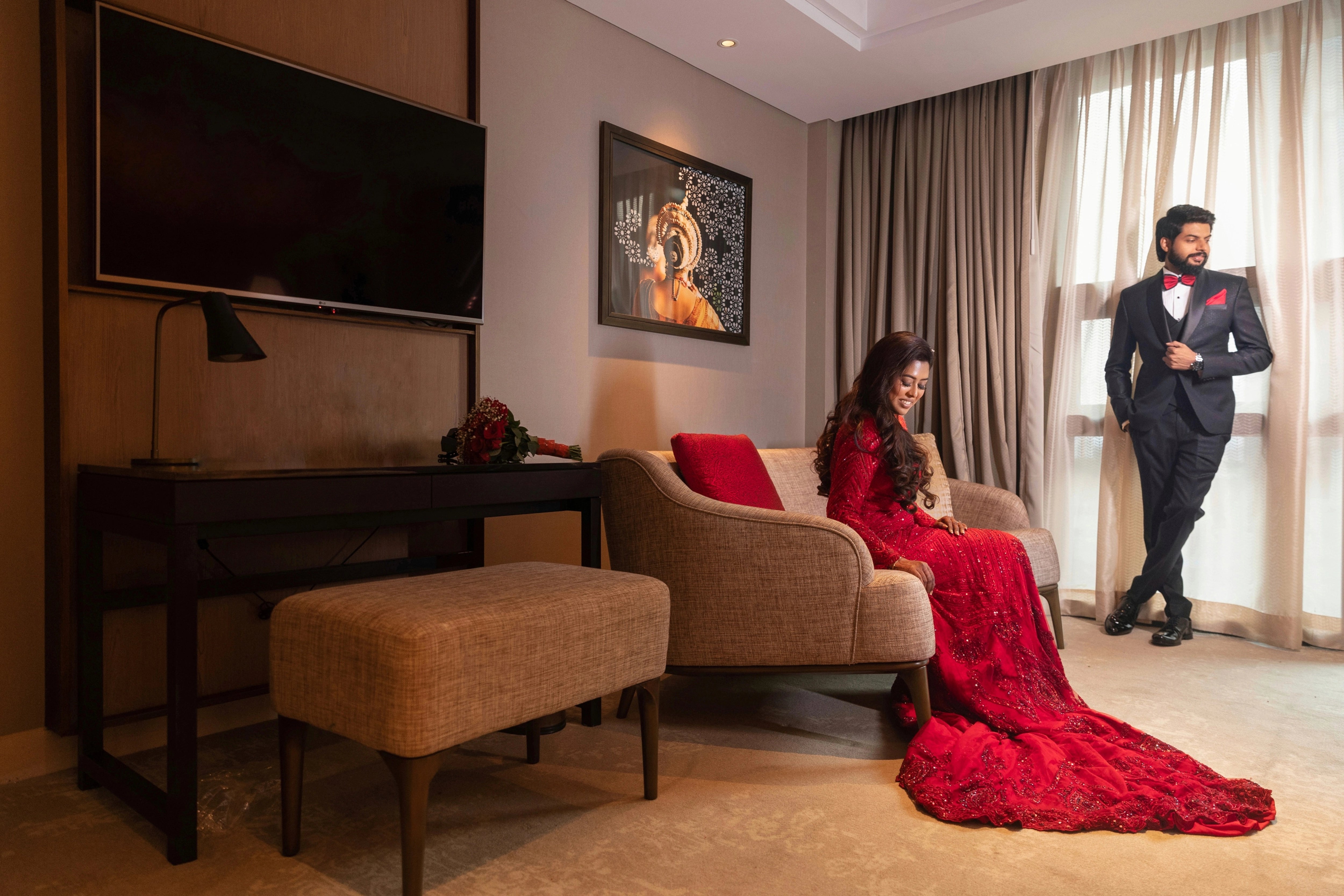 Dr Vishu Priya with groom in a ruby red mermaid gown intricately handcrafted by team Archana Karthick.