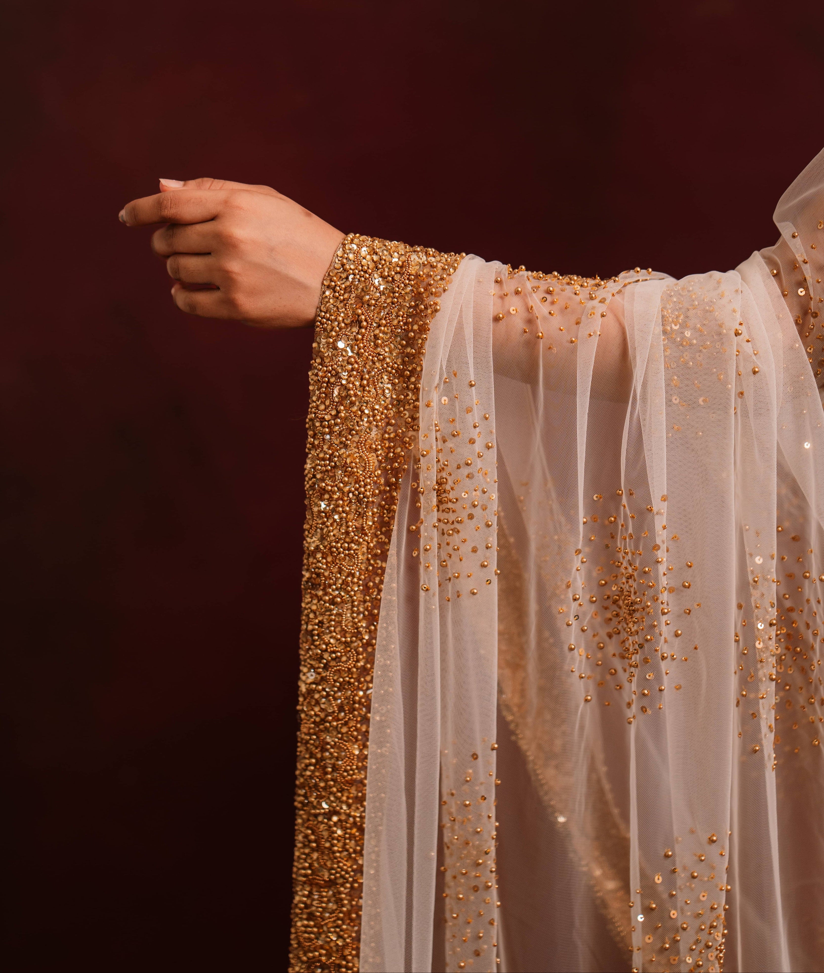 Drape design details of ivory tulle saree intricately handcrafted with antique gold beads and sequins paired with a handcrafted blouse featuring similar work by team Archana Karthick