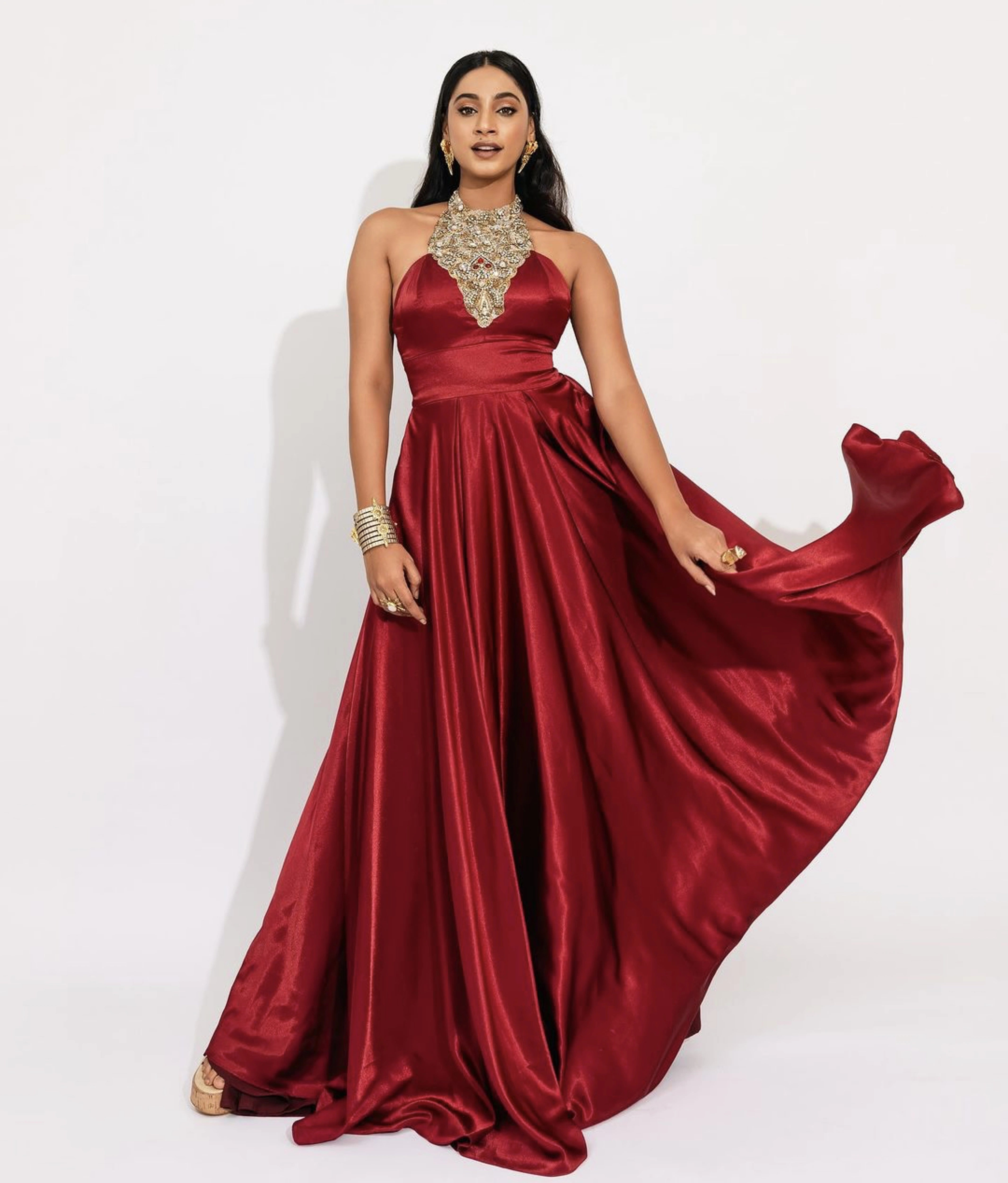 Former Miss India and Actress Anukreethy Vas smiling in a red satin silk bejewled halterneck gown by team Archana Karthick.