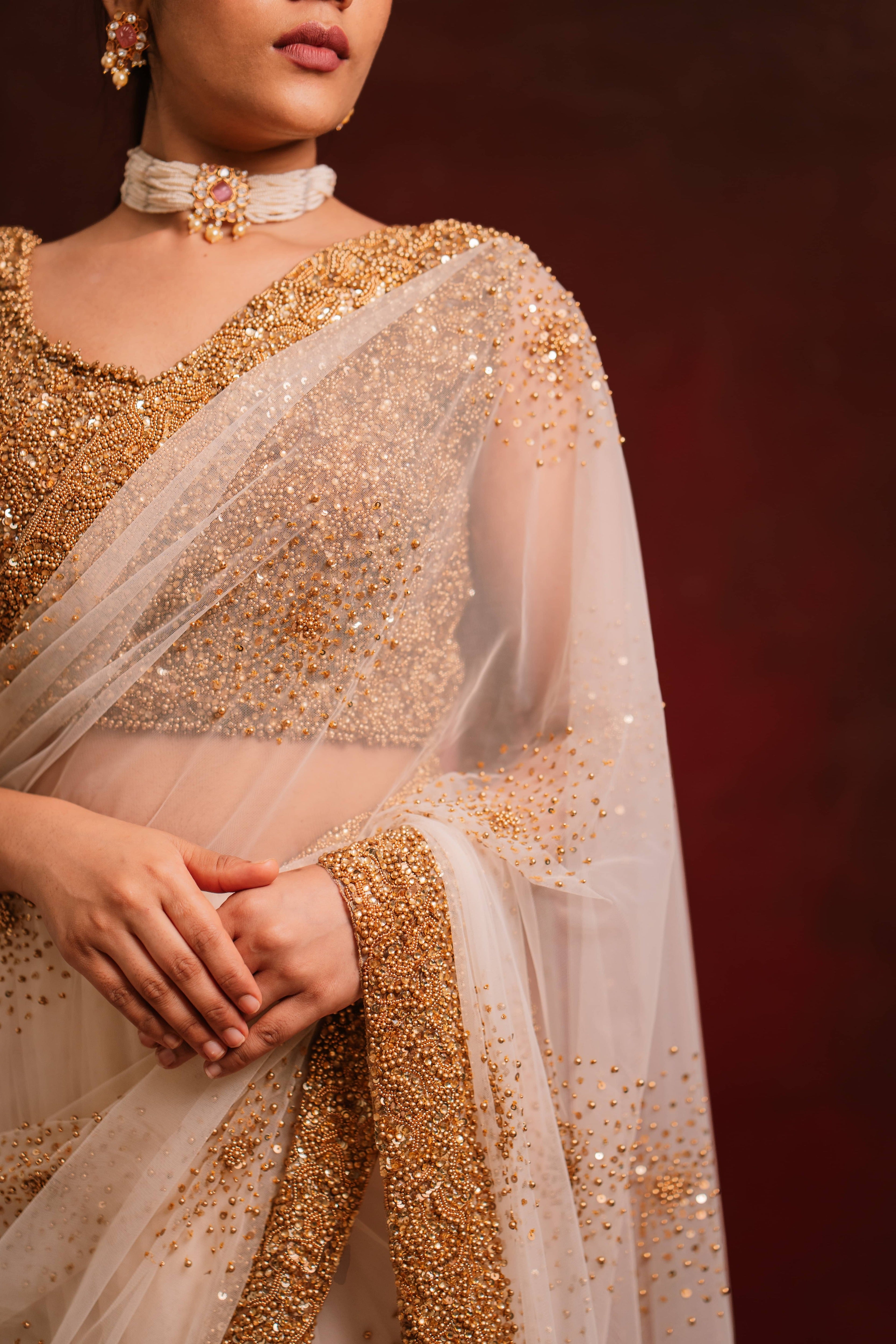 Front design details of ivory tulle saree intricately handcrafted with antique gold beads and sequins paired with a handcrafted blouse featuring similar work by team Archana Karthick