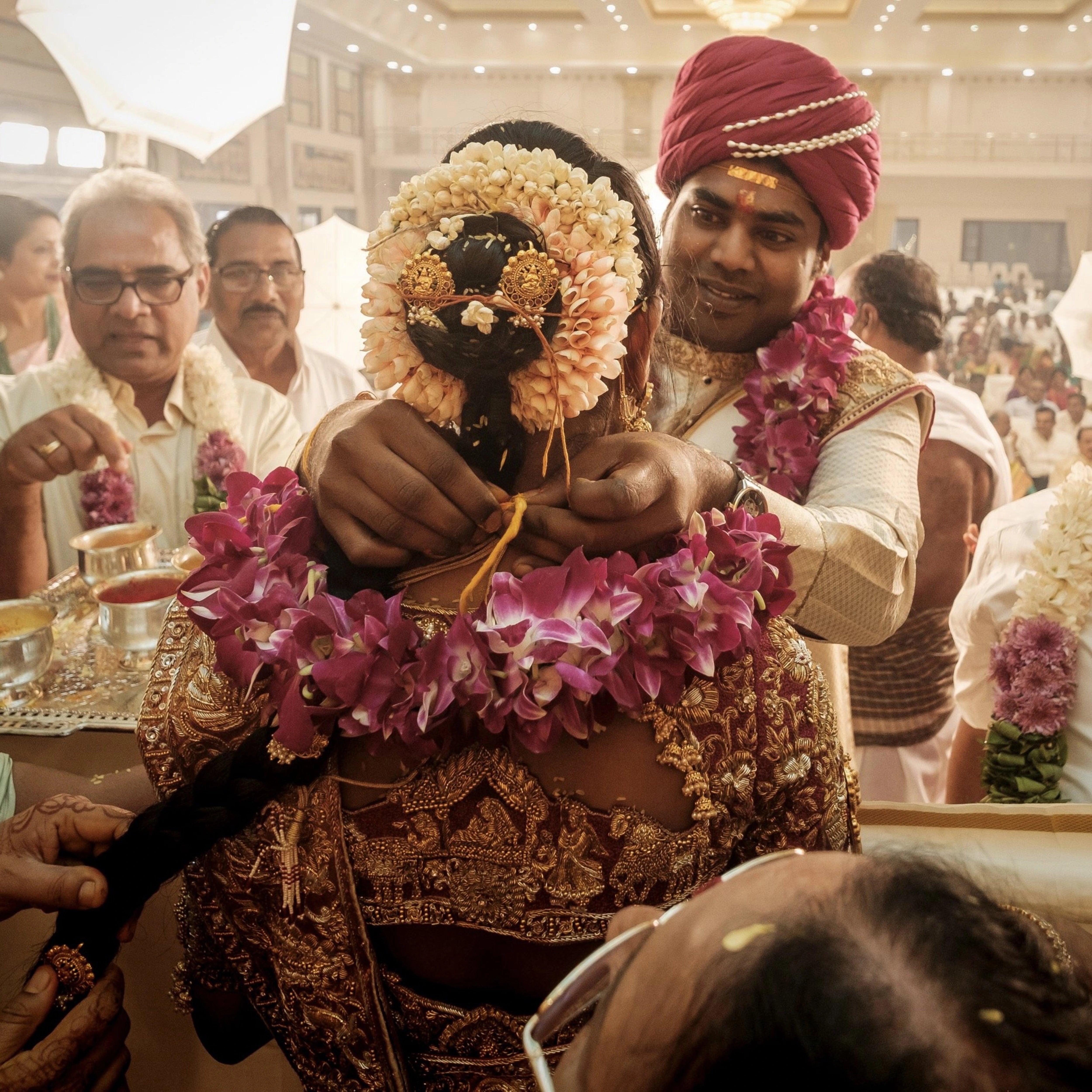 Groom Gowtham in a silk panchakacham suit, shawl and turban smiling at bride for his wedding, intricately handcrafted with zardosi, resham, zari and sequins by team Archana Karthick.