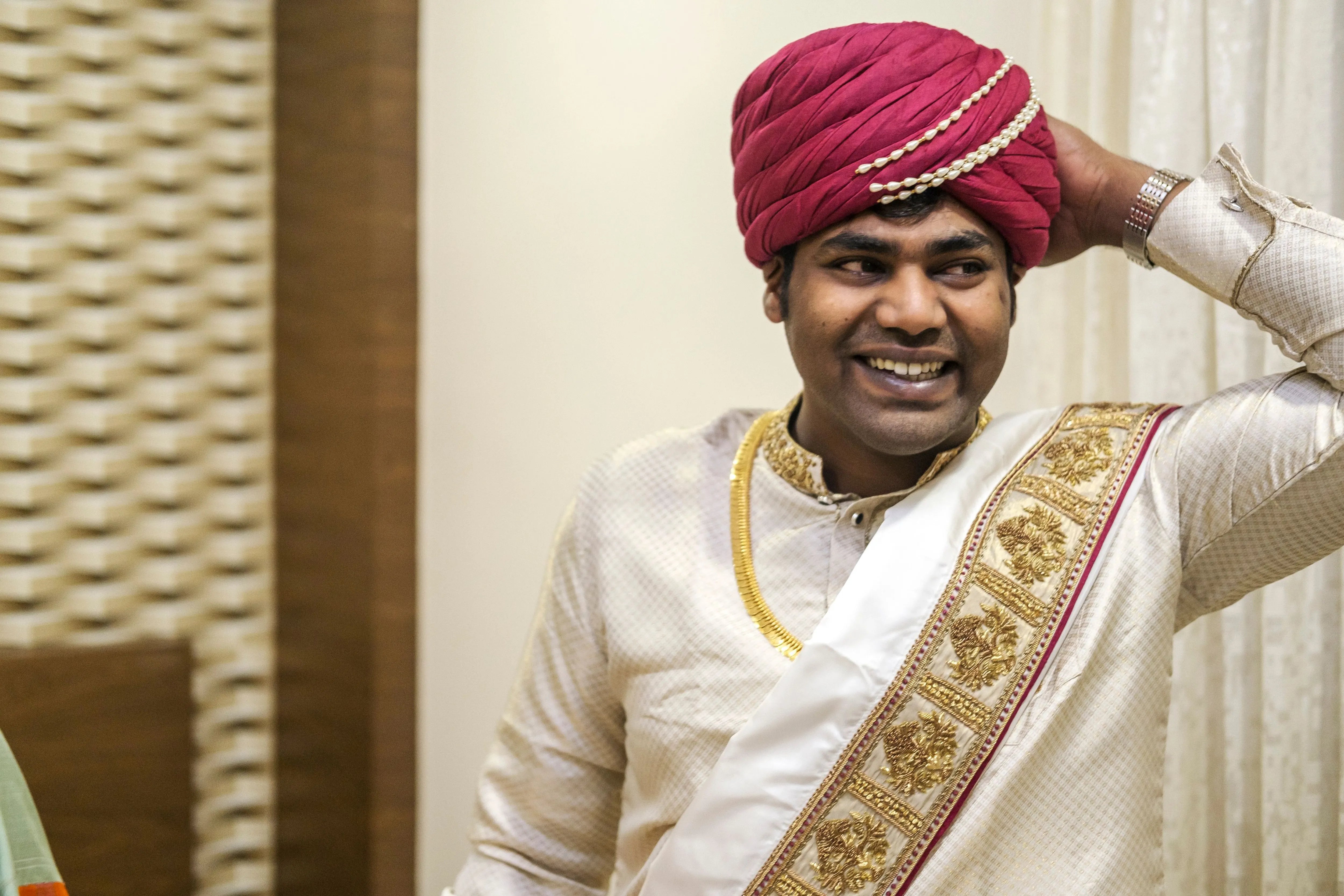 Groom Gowtham in a silk panchakacham suit, shawl and turban smiling for his wedding, intricately handcrafted with zardosi, resham, zari and sequins by team Archana Karthick.