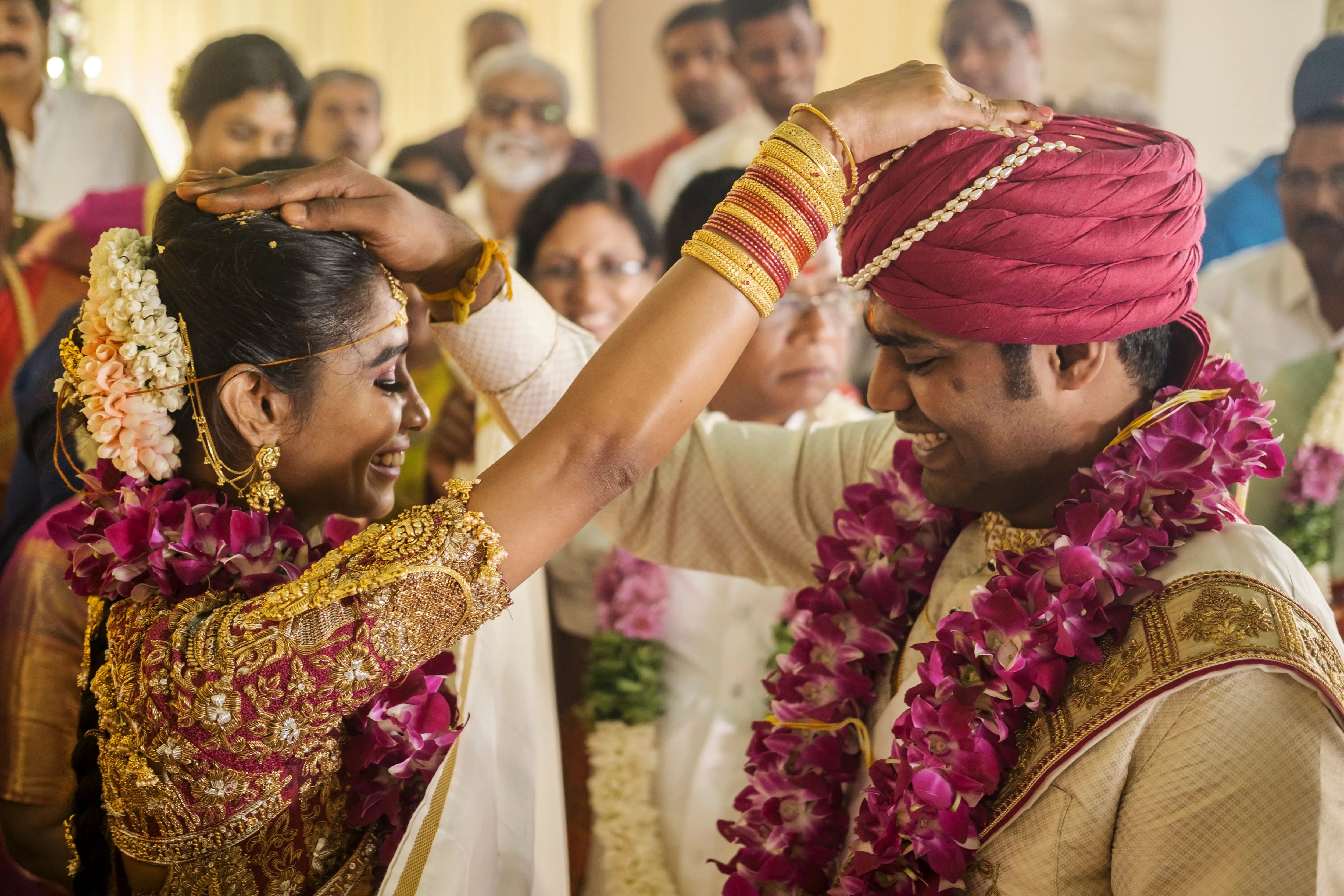Groom Gowtham in a silk panchakacham suit, shawl and turban smiling with bride for his wedding, intricately handcrafted with zardosi, resham, zari and sequins by team Archana Karthick.