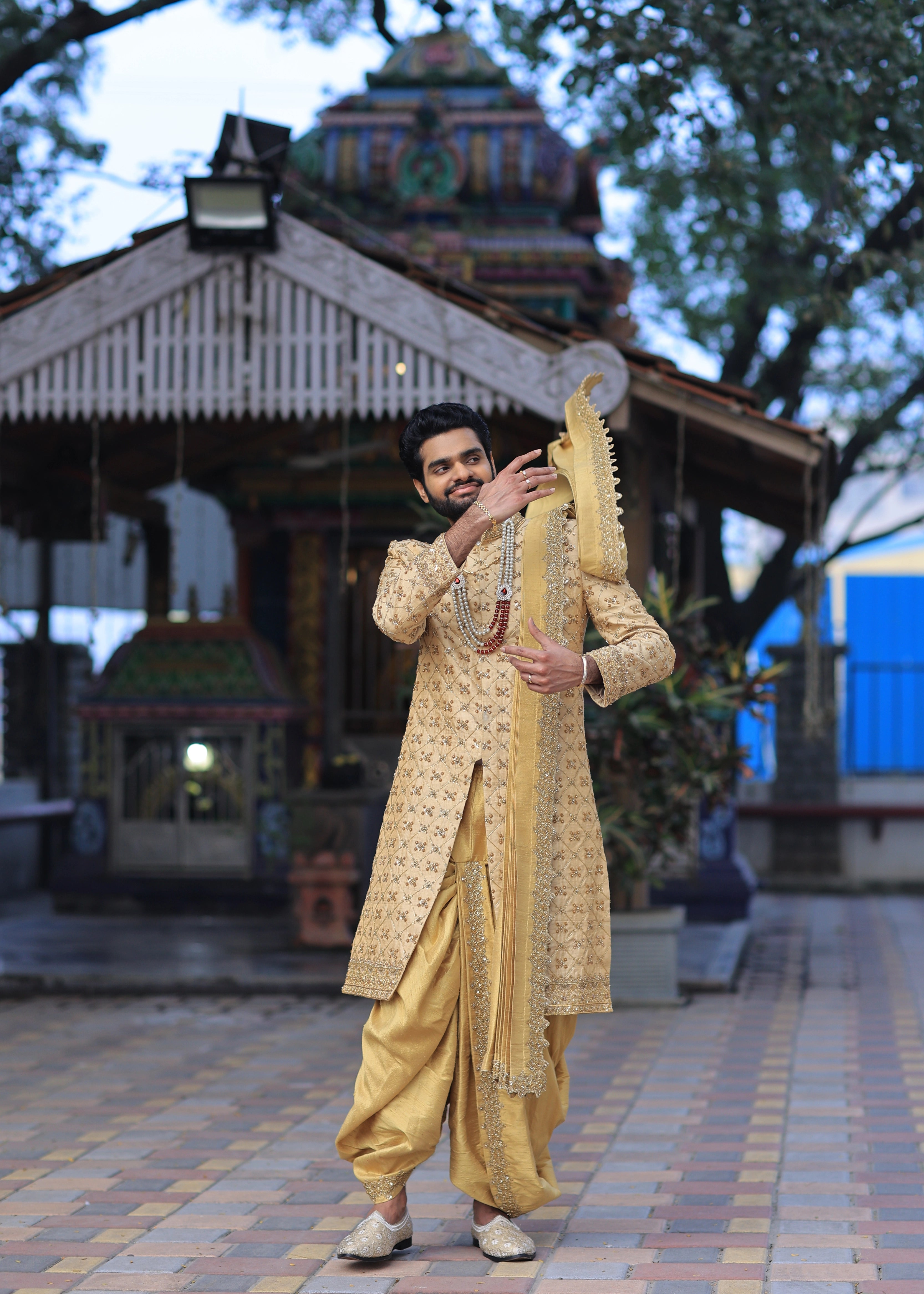 Groom from Canada posing in handcrafted gold sherwani by Archana Karthick