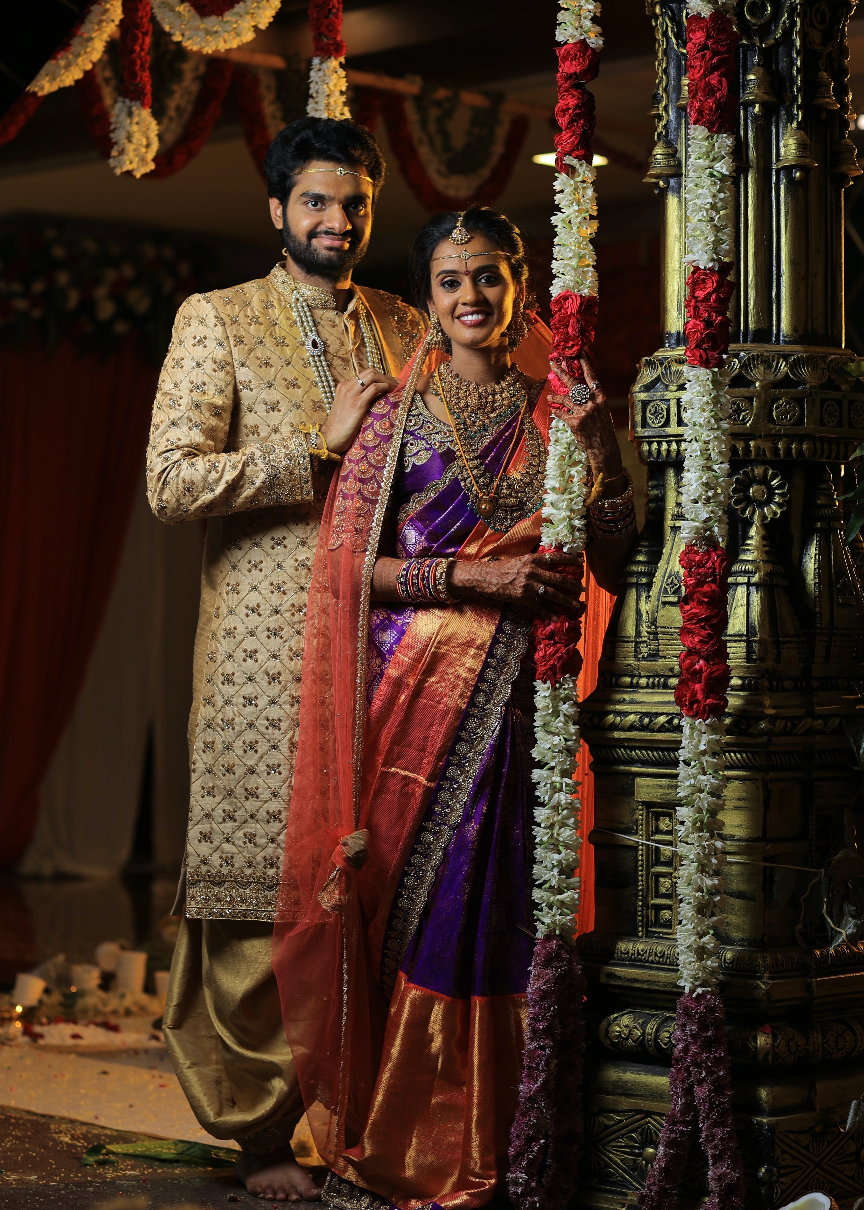 Groom from Canada posing with bride in handcrafted gold sherwani by Archana Karthick