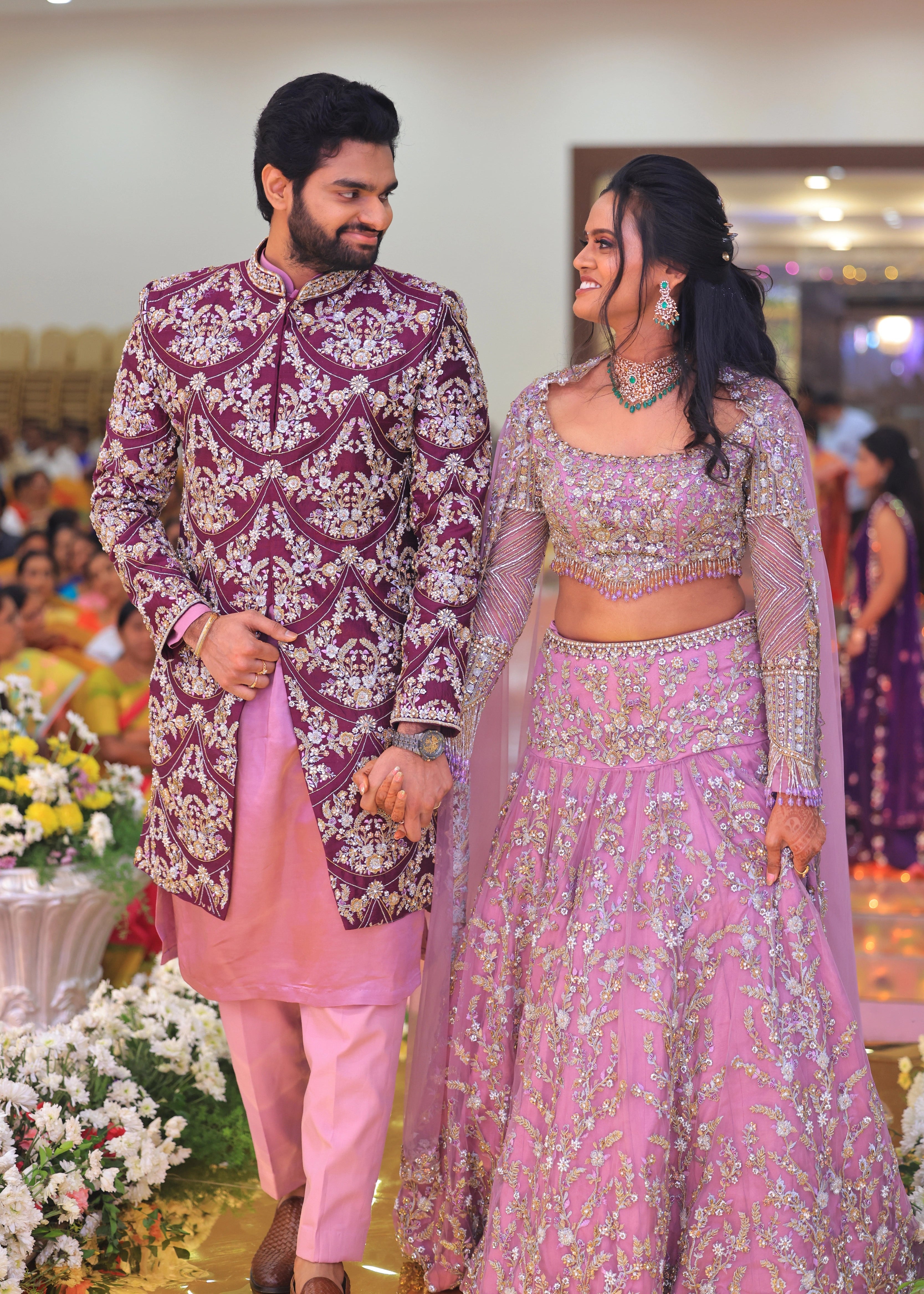 Groom from Canada walking with bride in handcrafted purple sherwani by Archana Karthick
