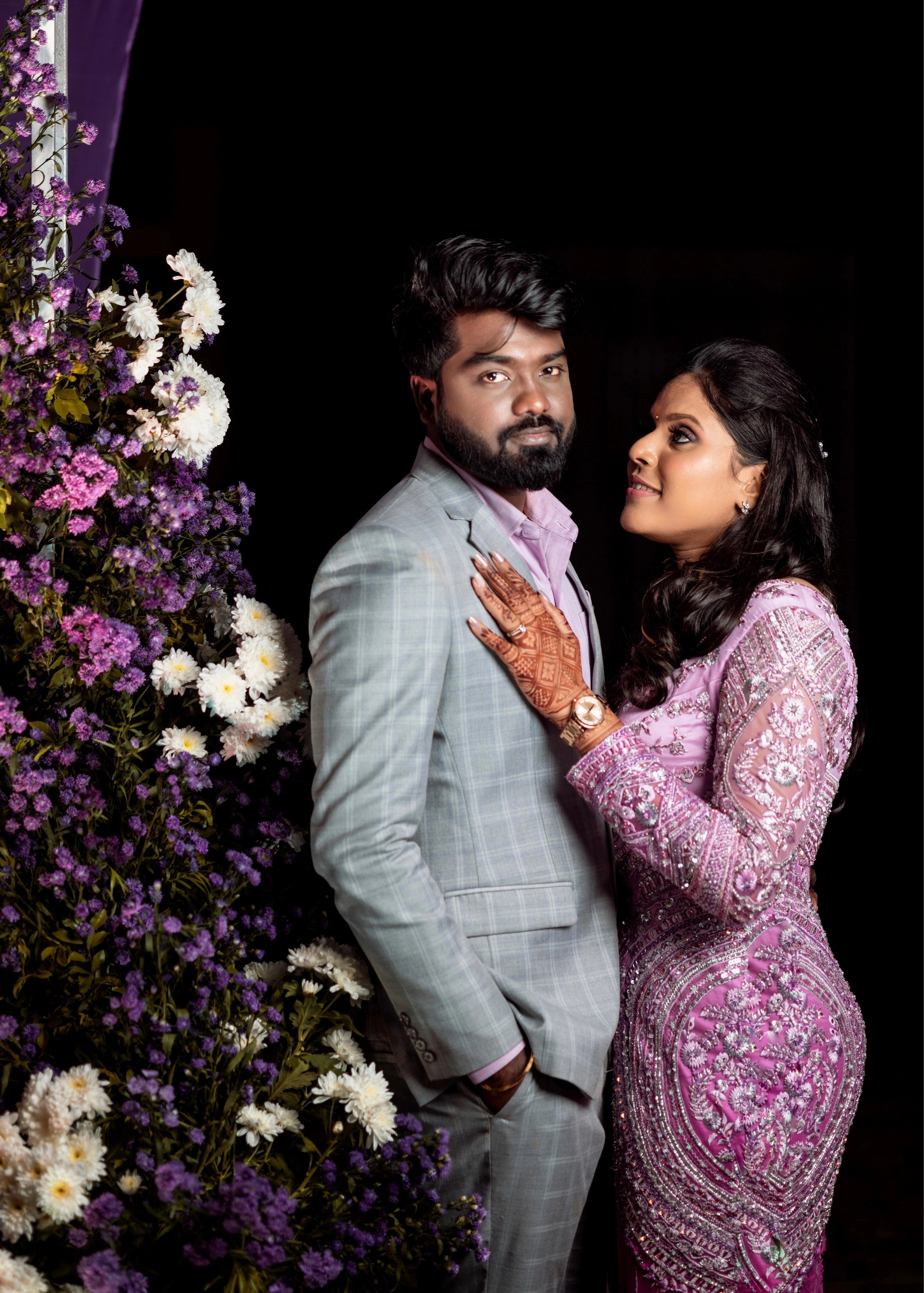 Groom posing with bride in a custom three piece gray suit designed by Archana Karthick